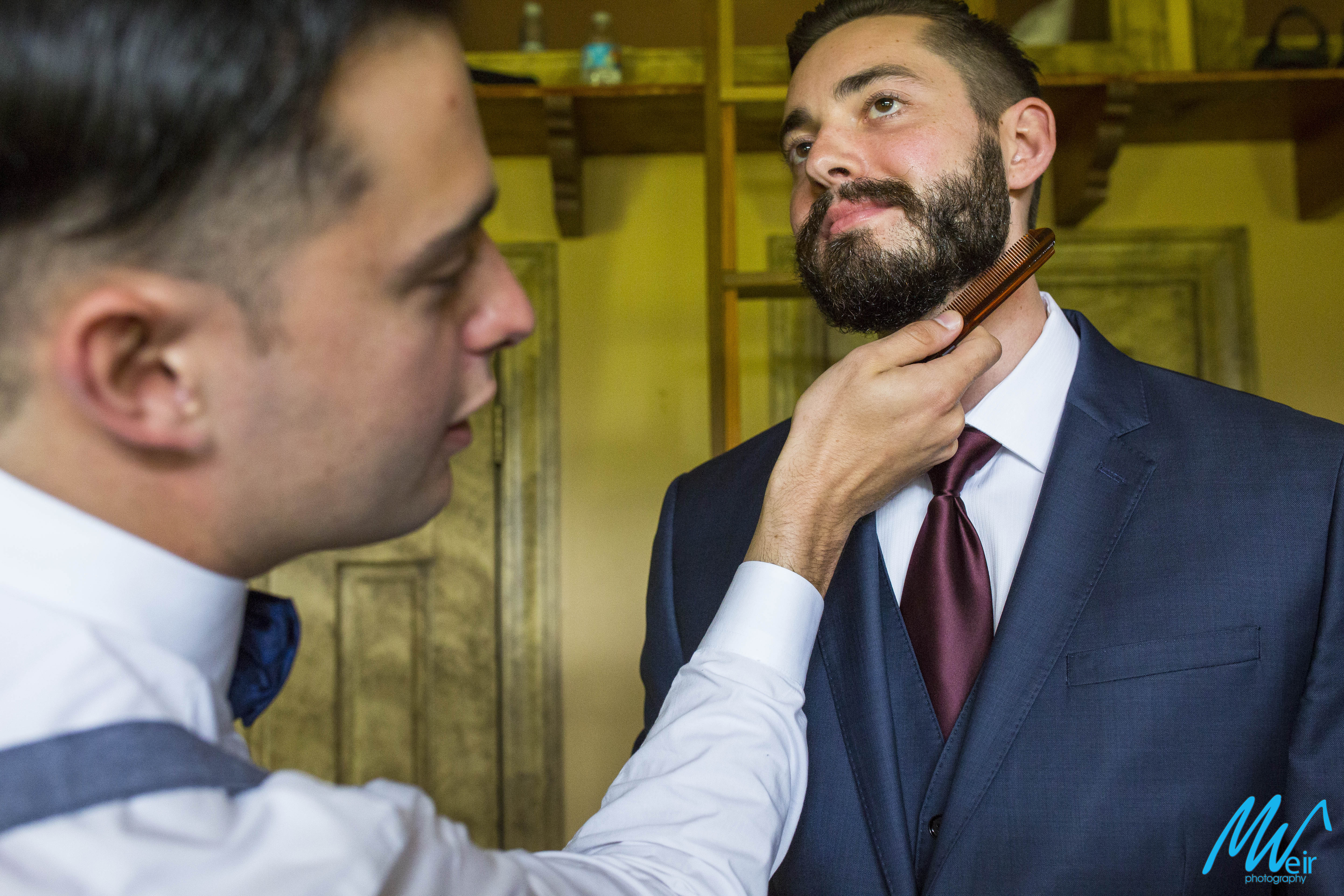 groomsman brushes grooms beard with a comb
