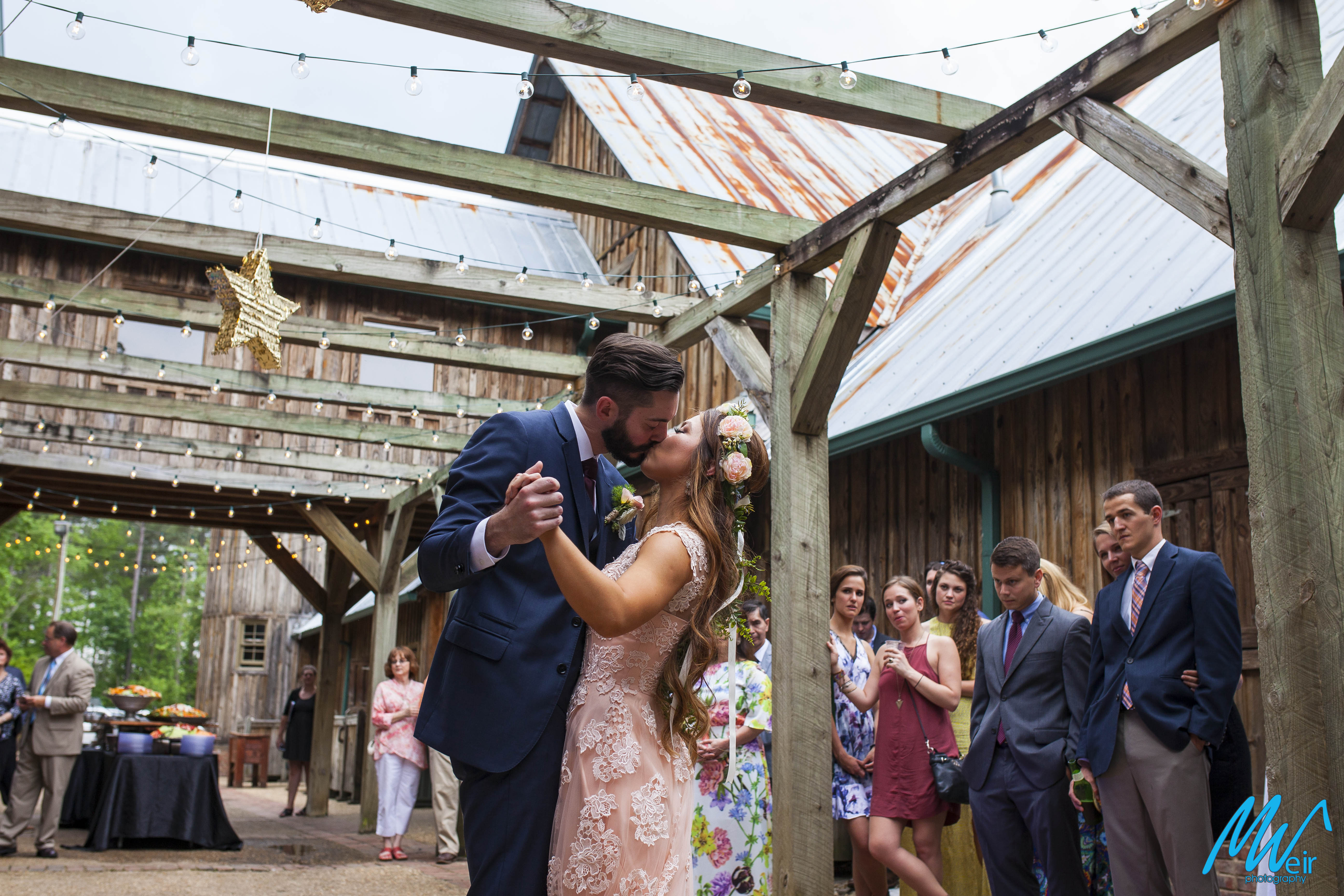 bride and groom share a first dance under wood arbor outside under star pinatas