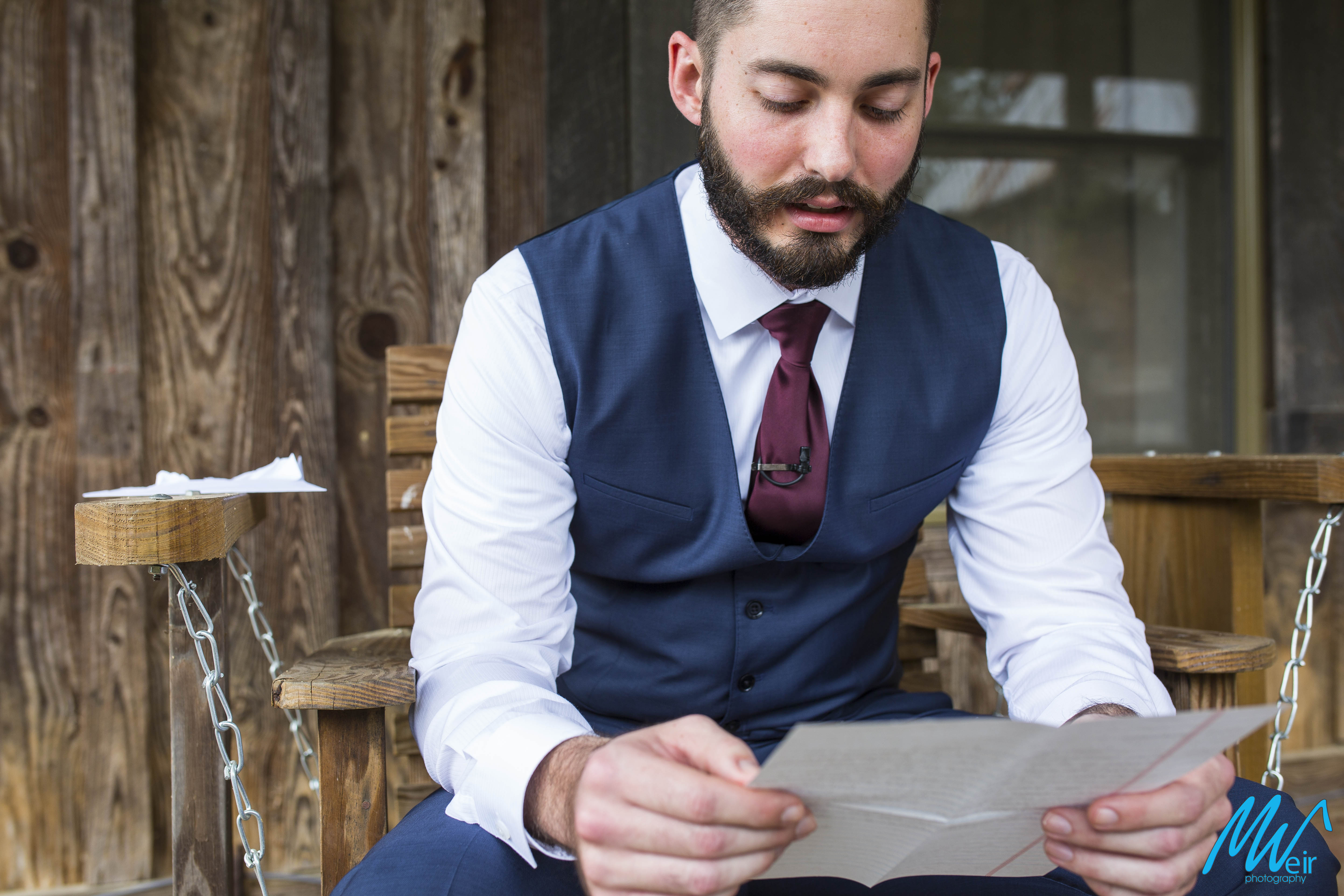 groom reads a letter from his bride before ceremony