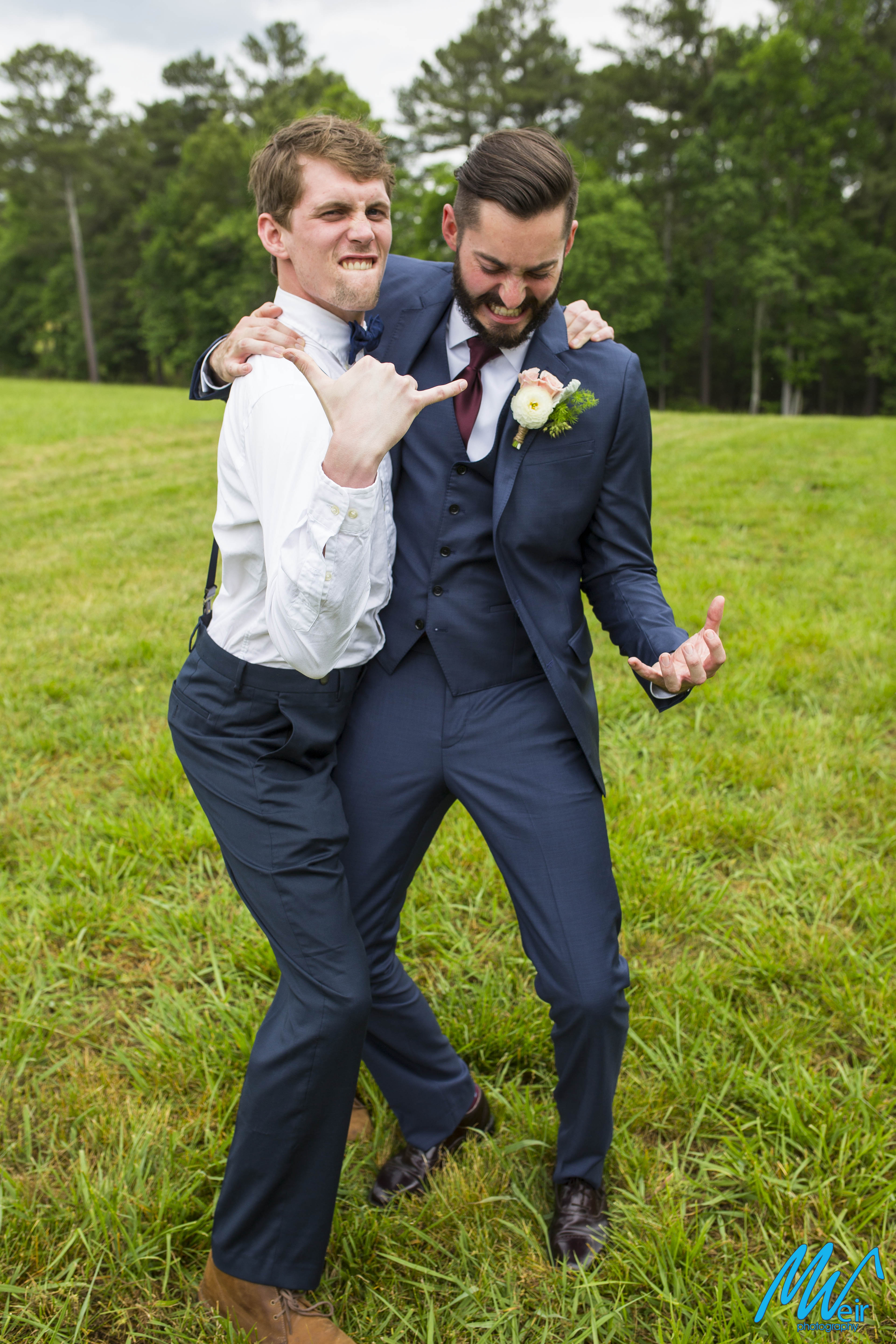 groom and groomsmen strike a funny pose in a field