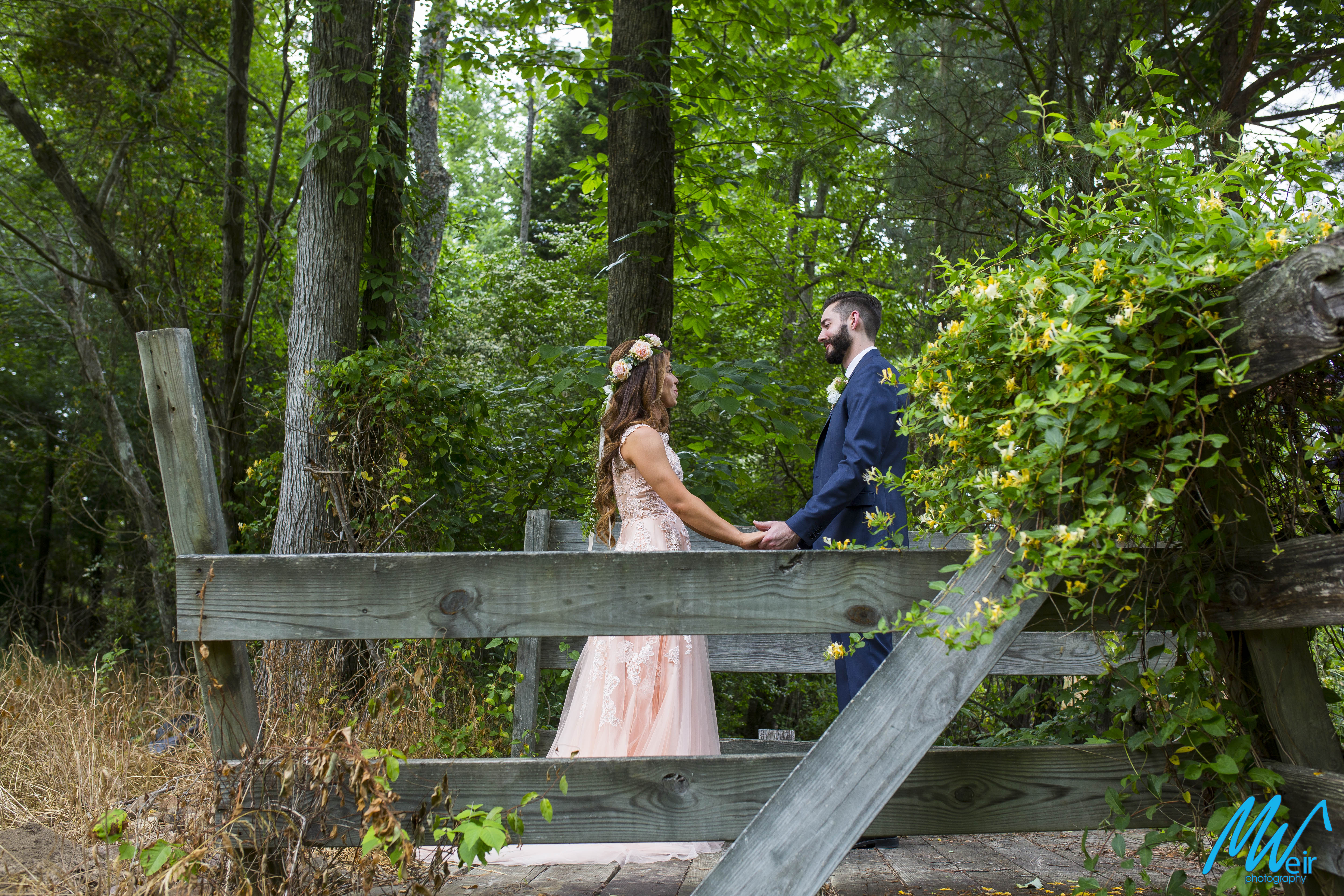 bride and groom hold hands during first look on a bridge