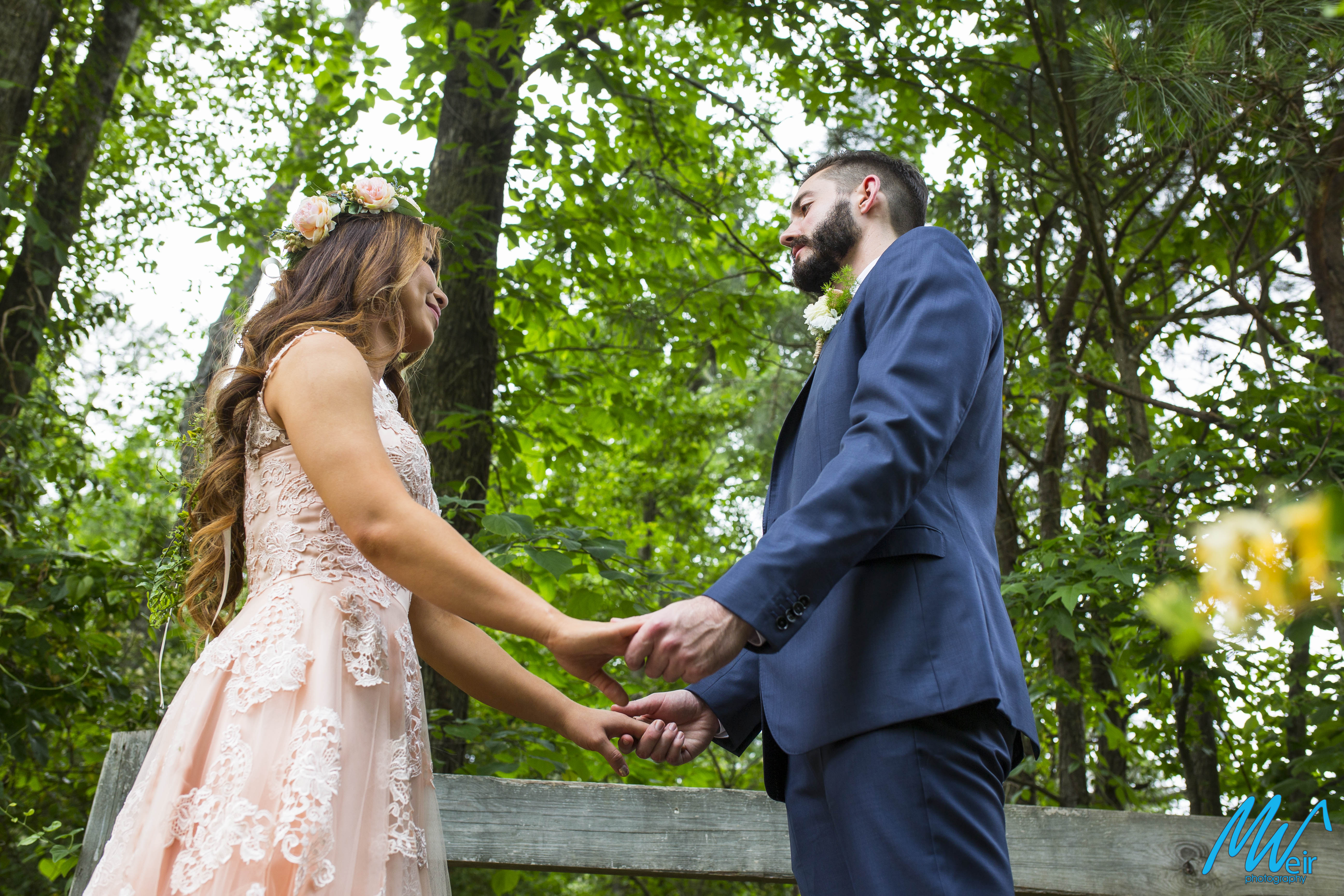 bride and groom hold hands during first look on a bridge