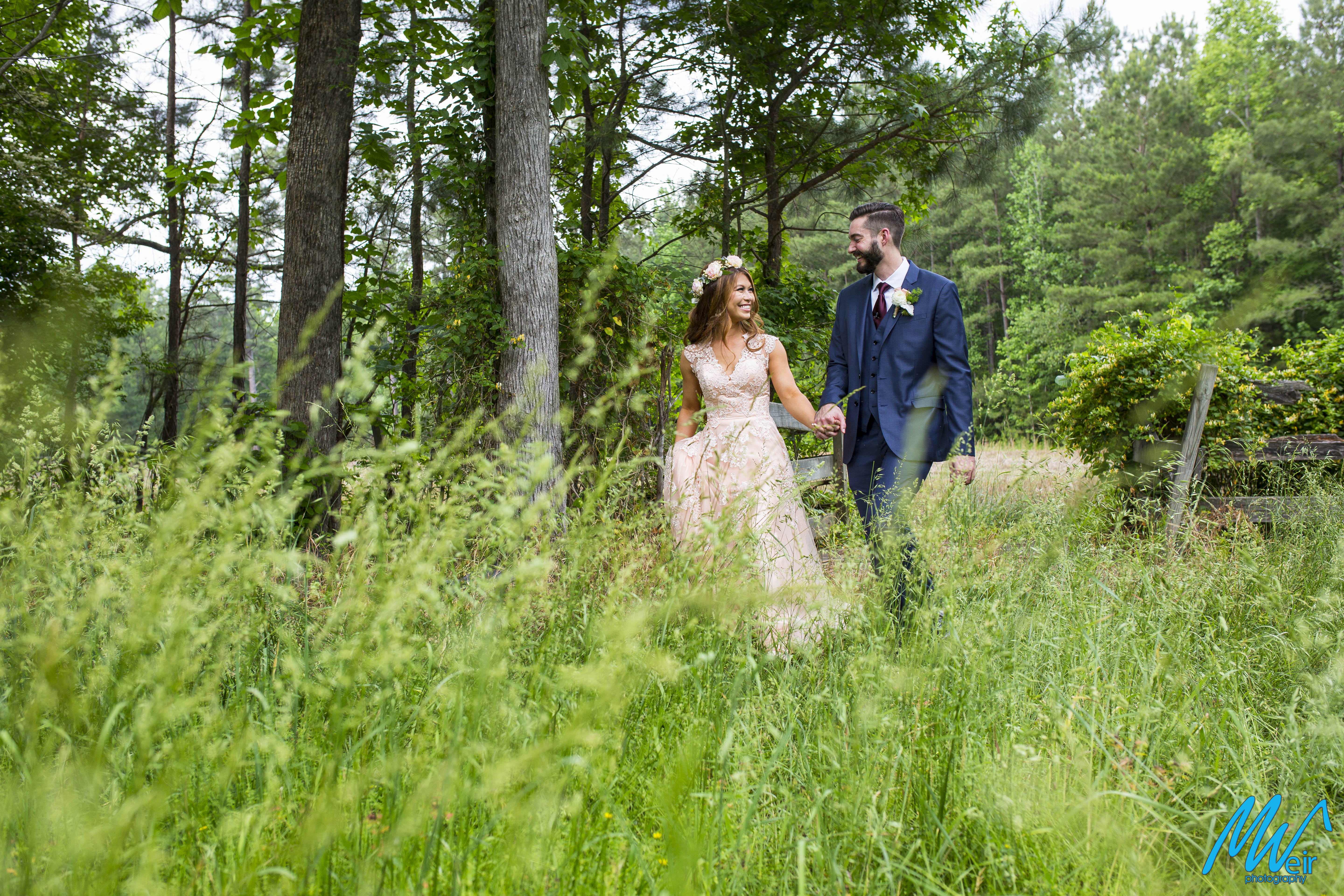 Bride and groom walk through a field