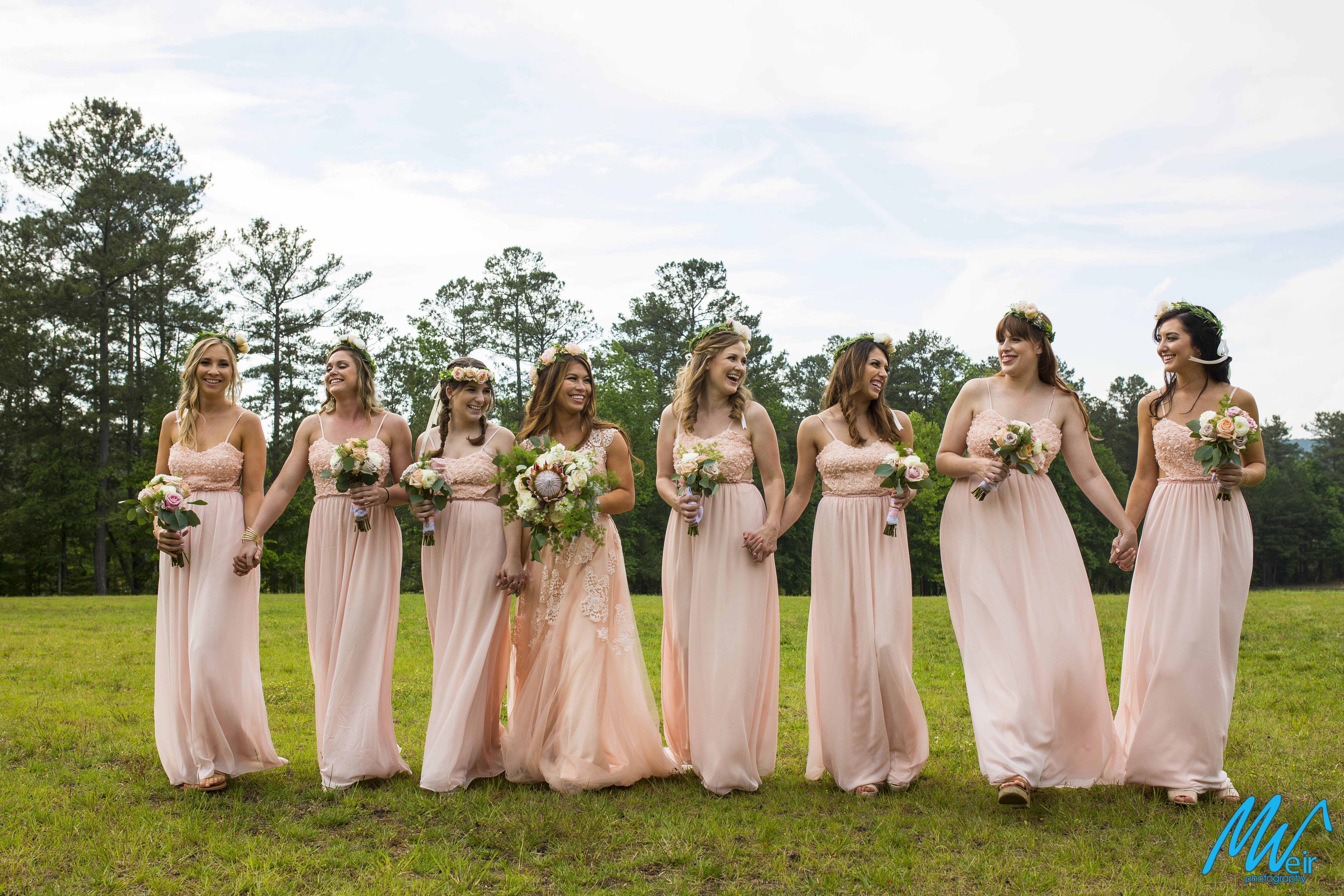 bohemian hipster Bridesmaids in pale pink dresses standing in a field