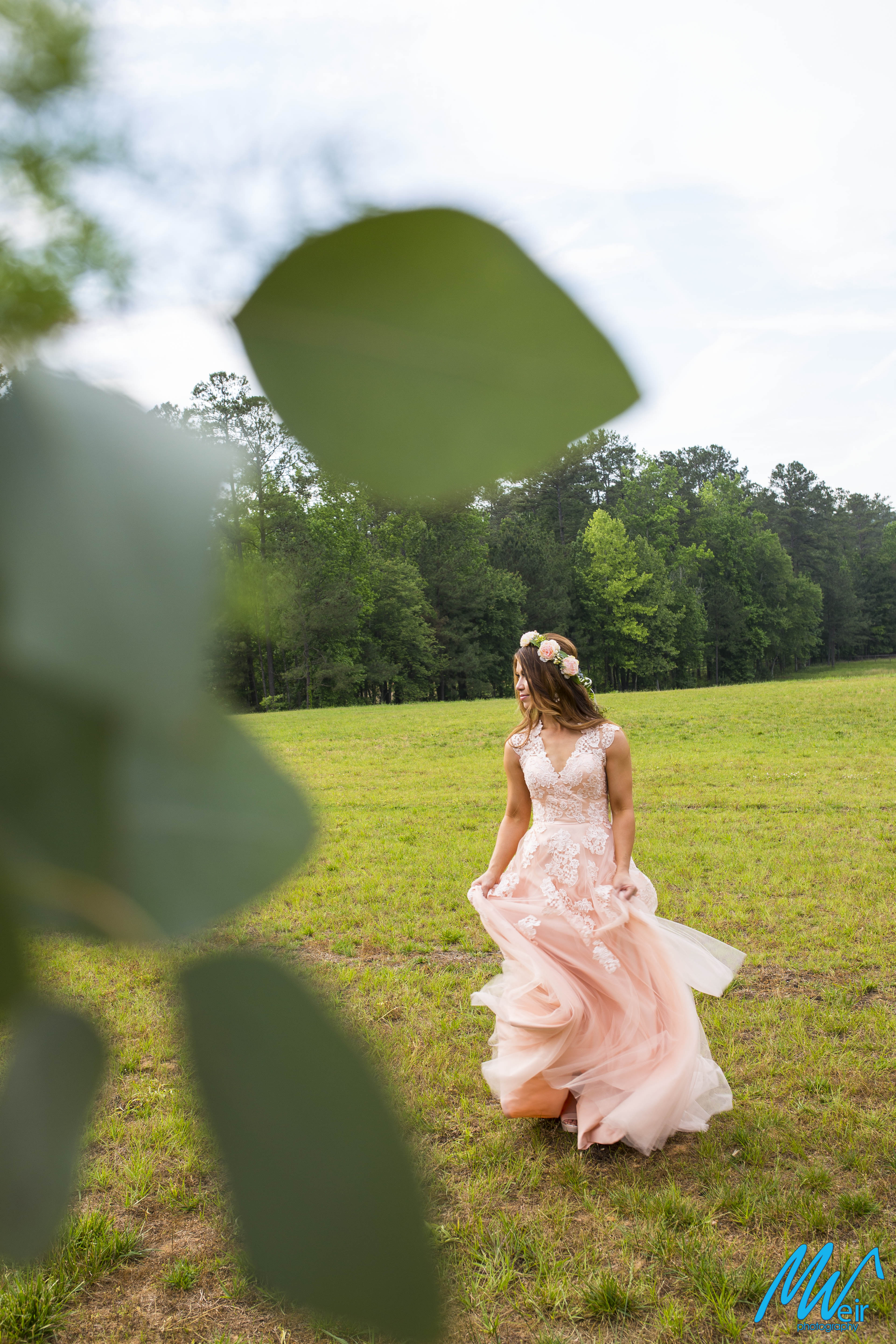 Bride playing with her dress in a field