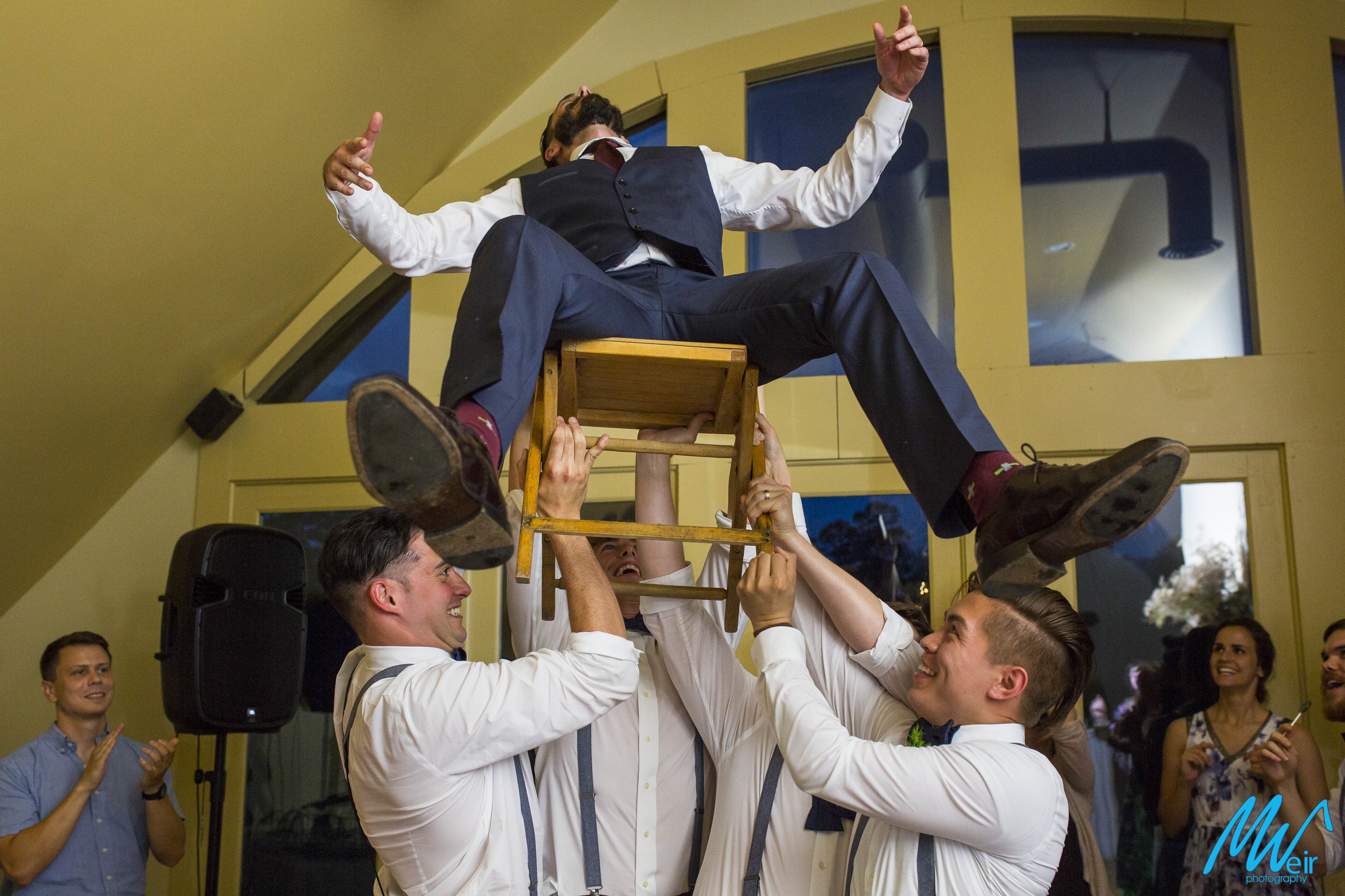 groom lifted on a chair during wedding reception dancing