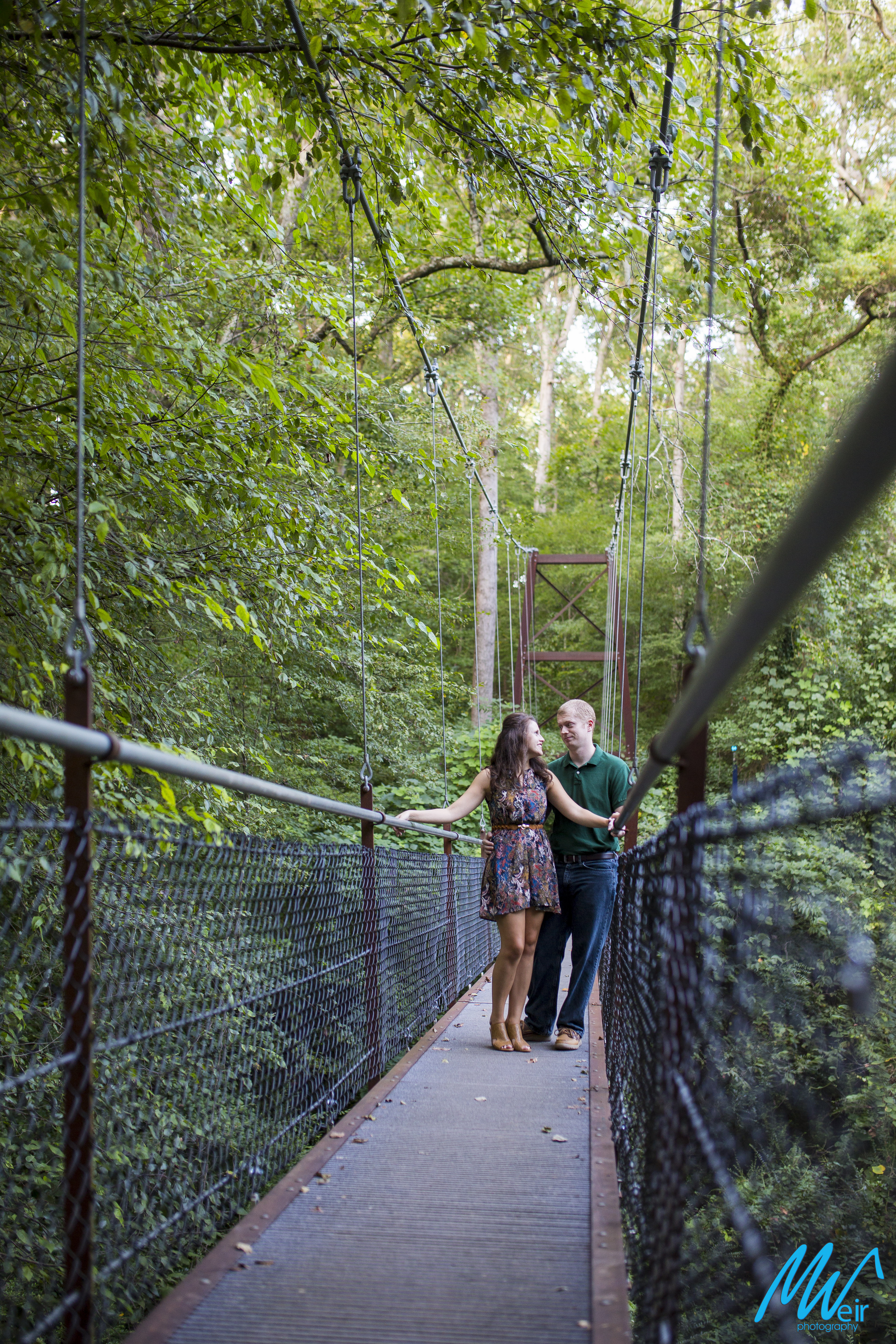 bride and groom hang out on a suspension bridge looking at each other