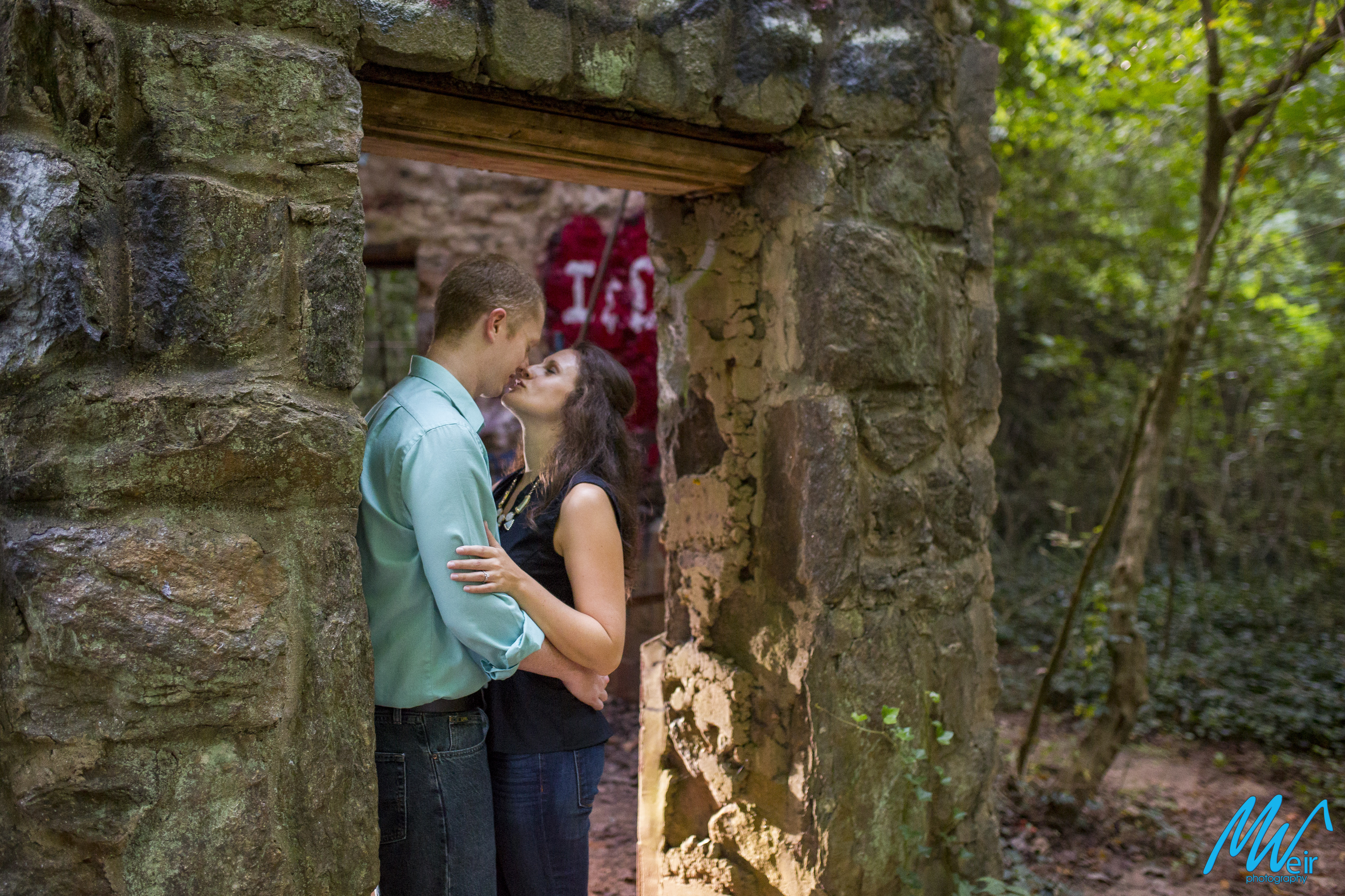 bride and groom kiss each other a stone door way
