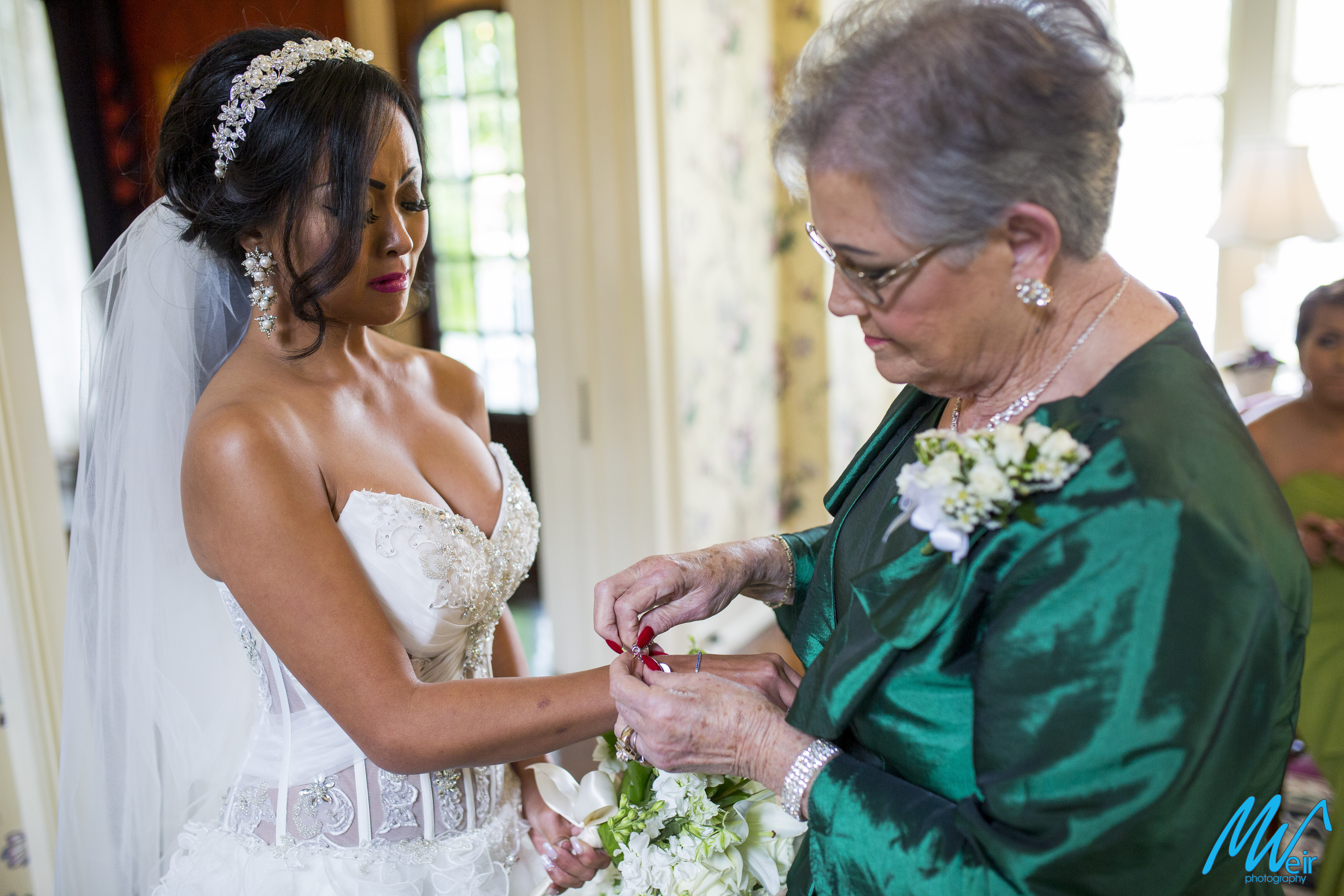 mother of the groom puts her charm bracelet on brides wrist as her something borrowed