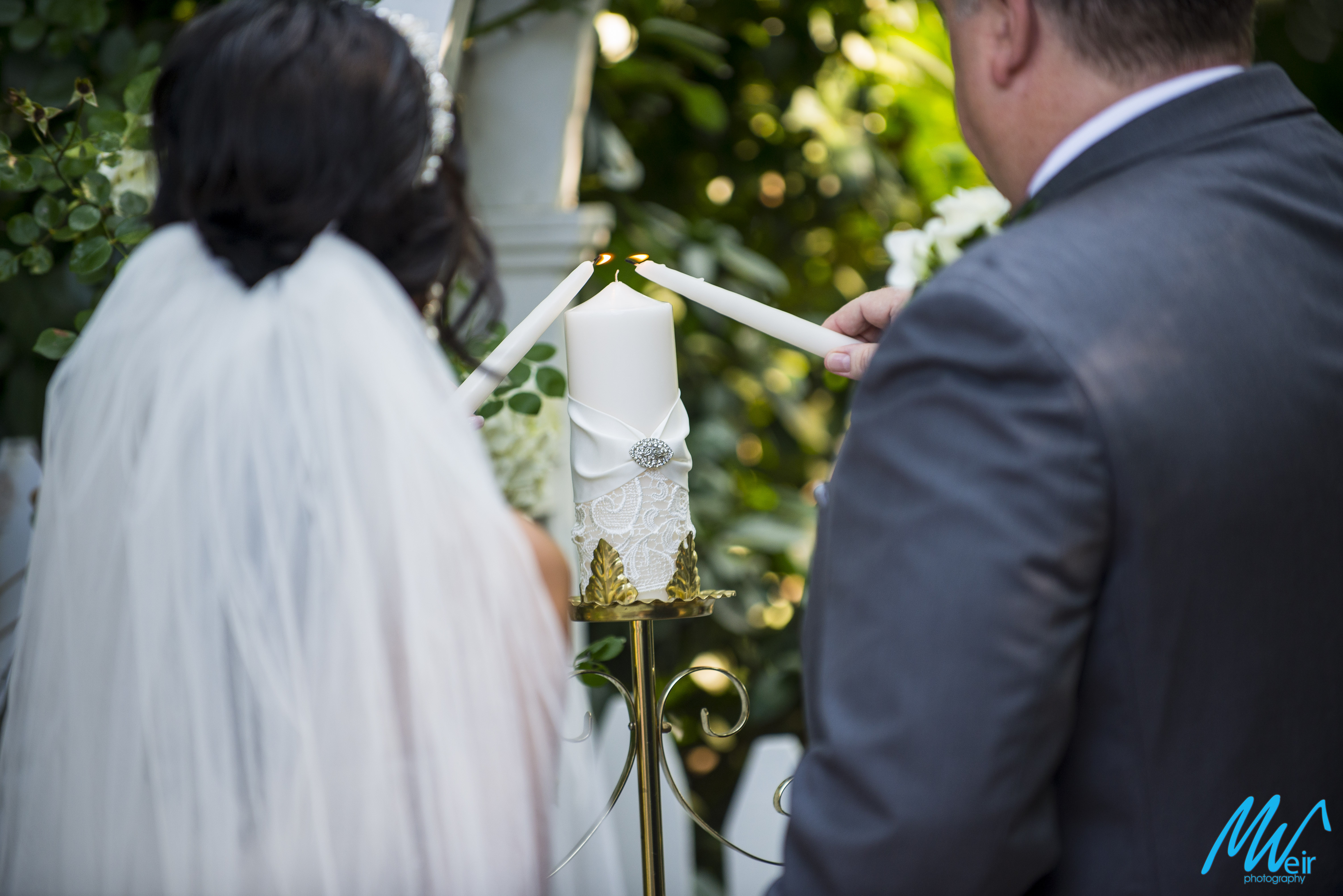 bride and groom light a unity candle during wedding ceremony