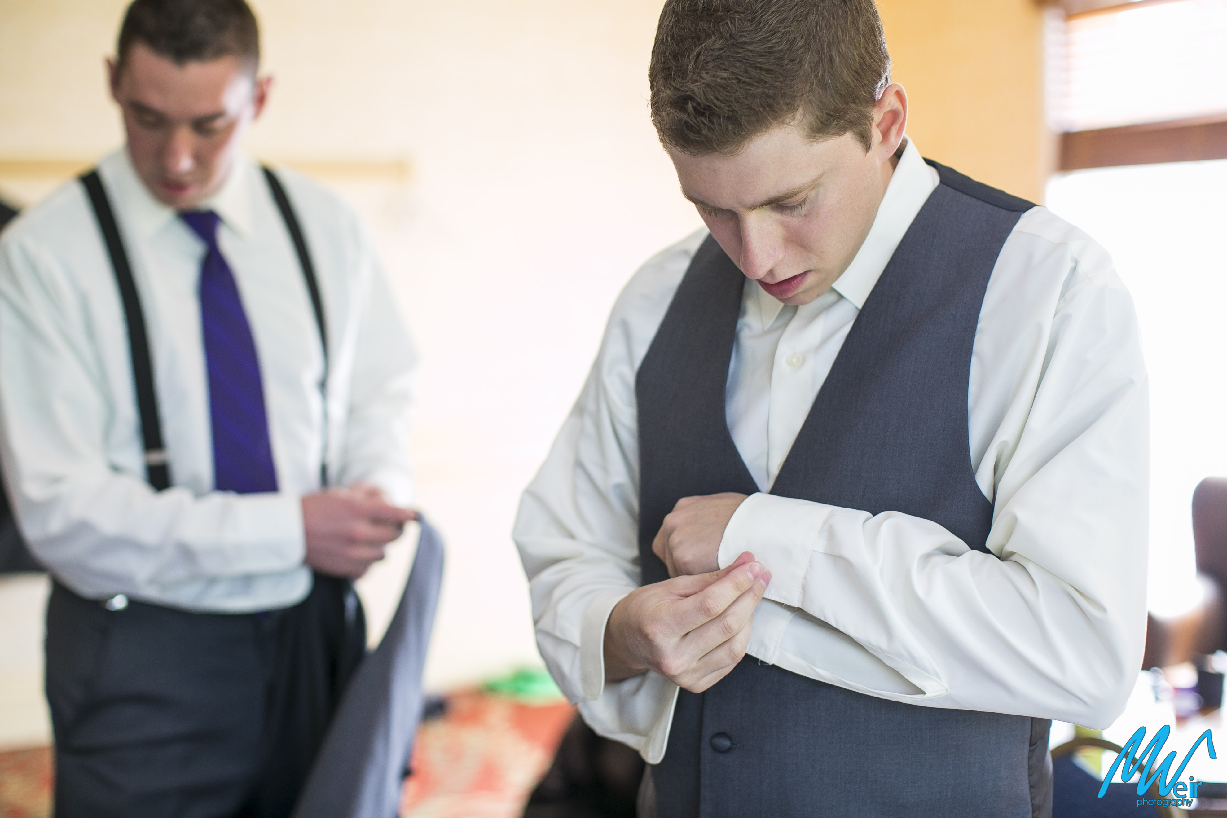 groom buttoning his shirt sleeve