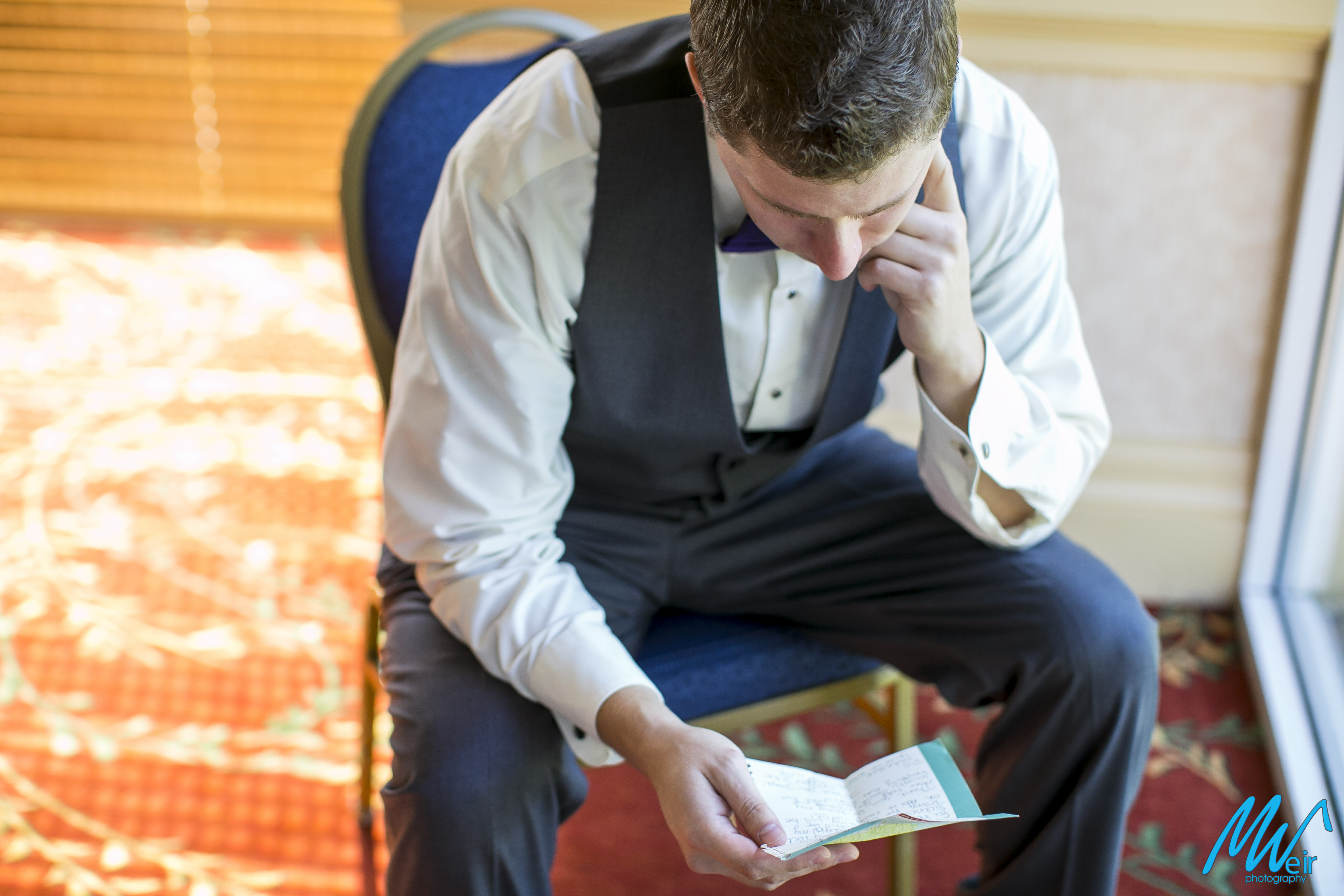 groom reading a note in hotel room from his bride