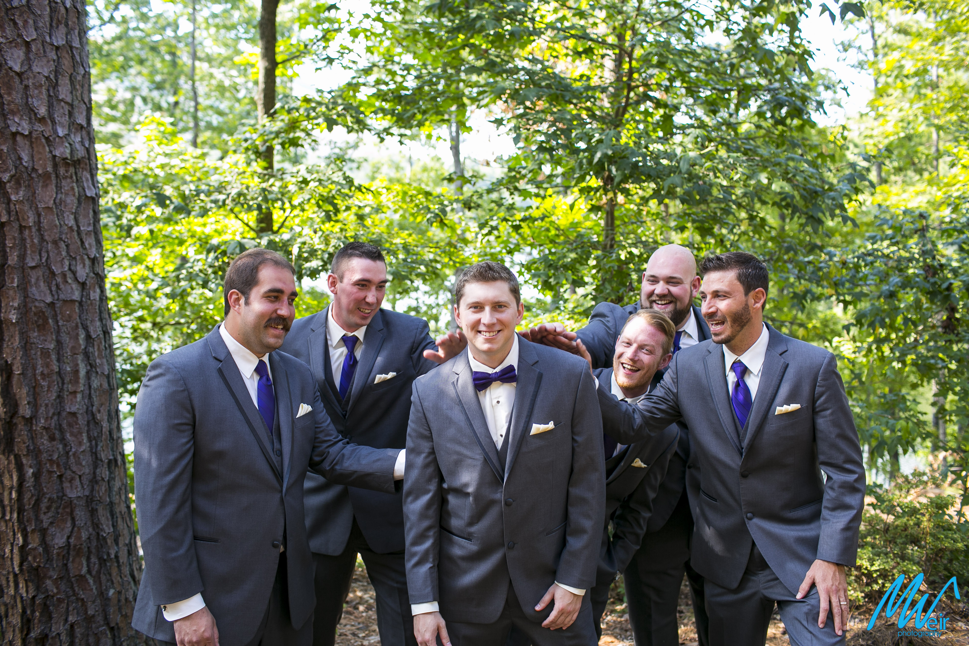 groomsmen give groom a jovial pat on the back in the woods