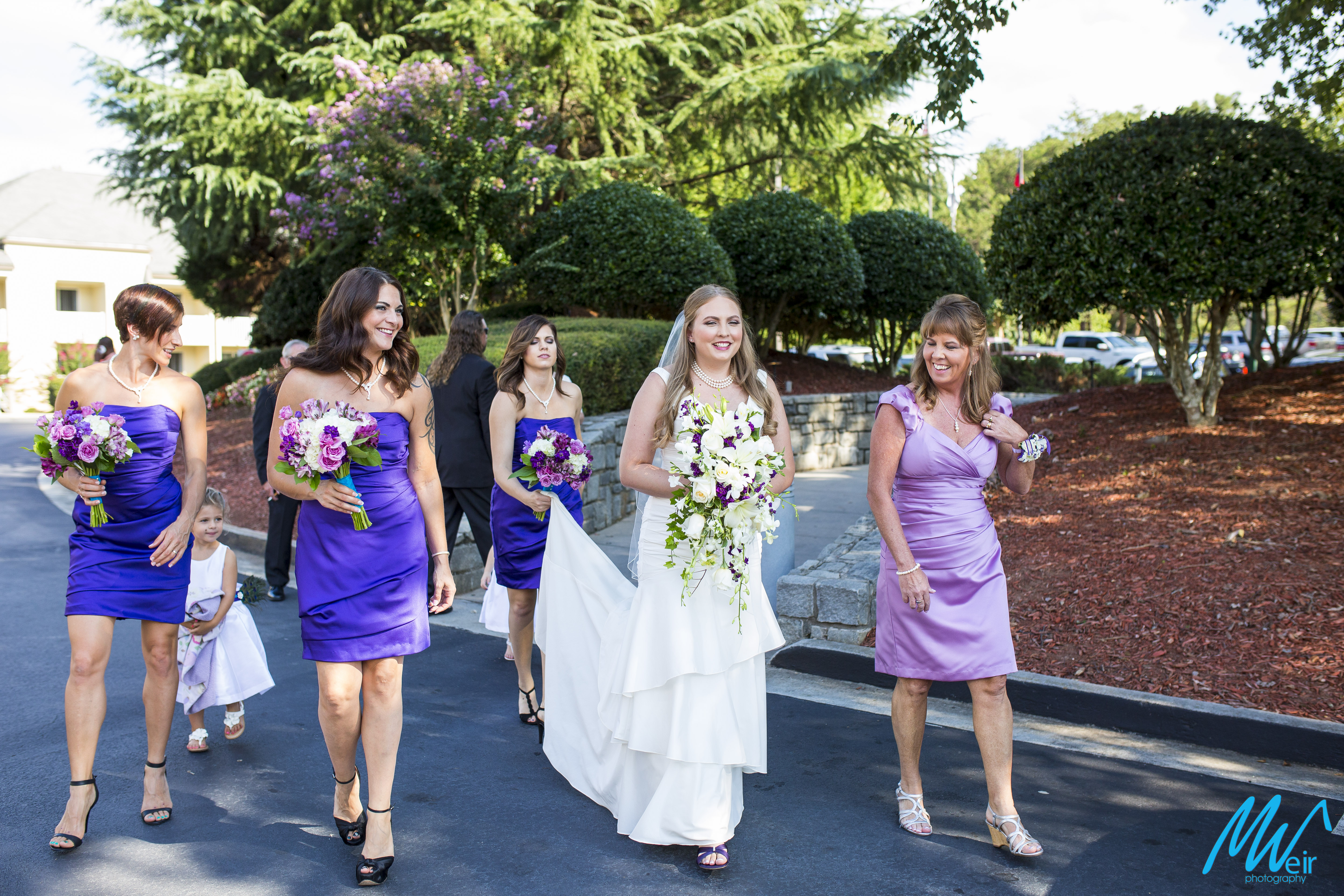 bride walks on road to her lakeside reception