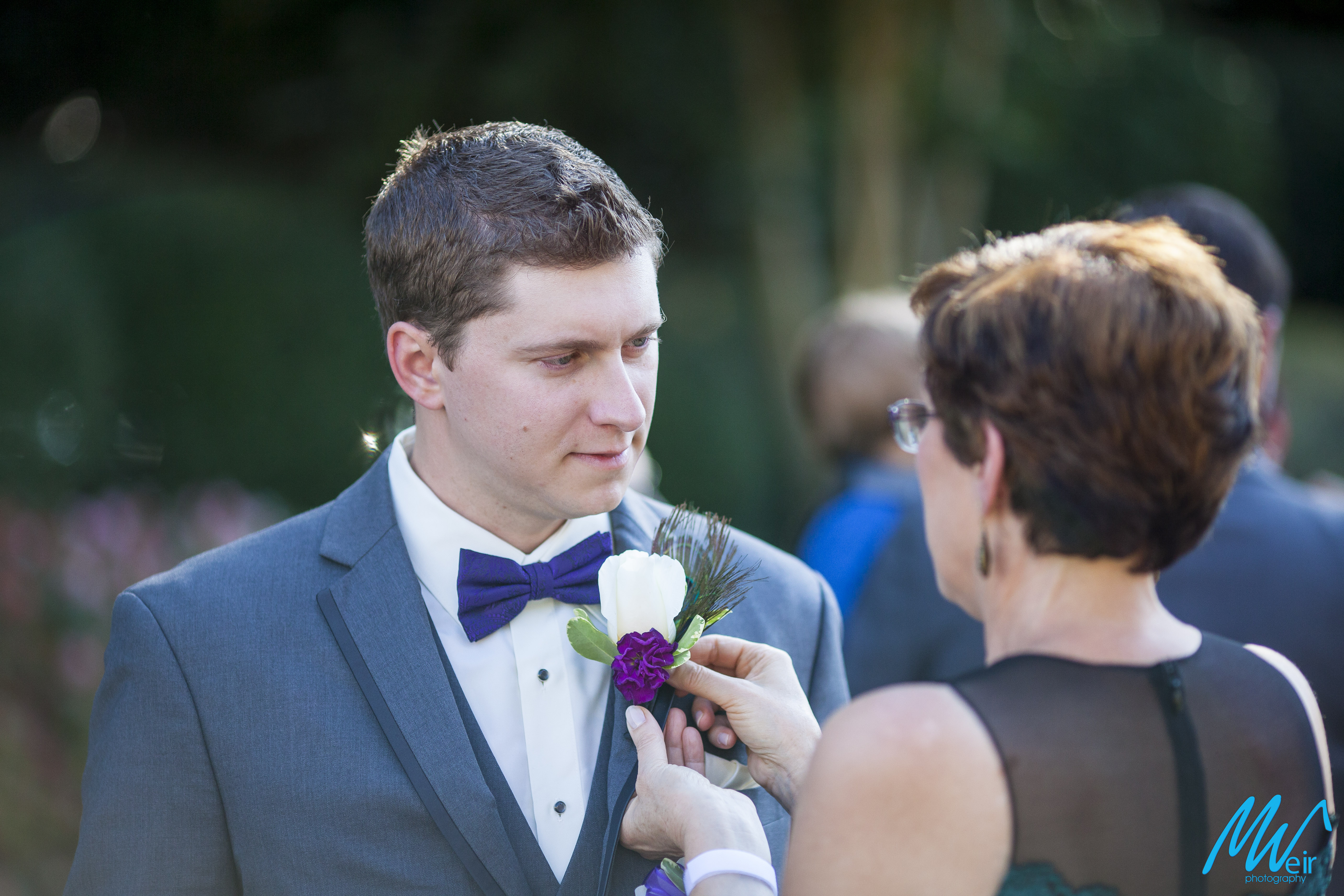 mother of the groom pins boutonniere on groom