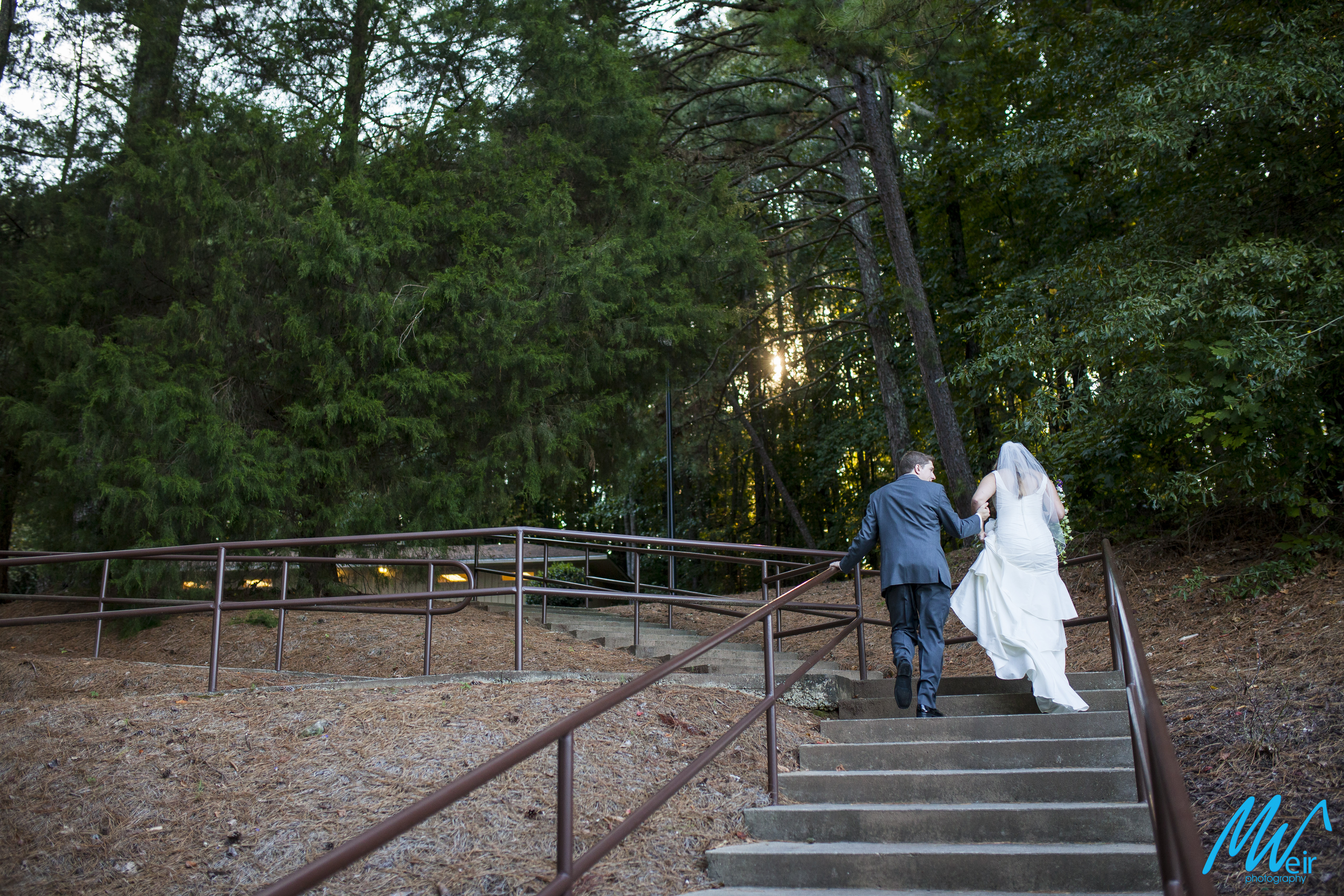 bride and groom walk up staircase after wedding ceremony