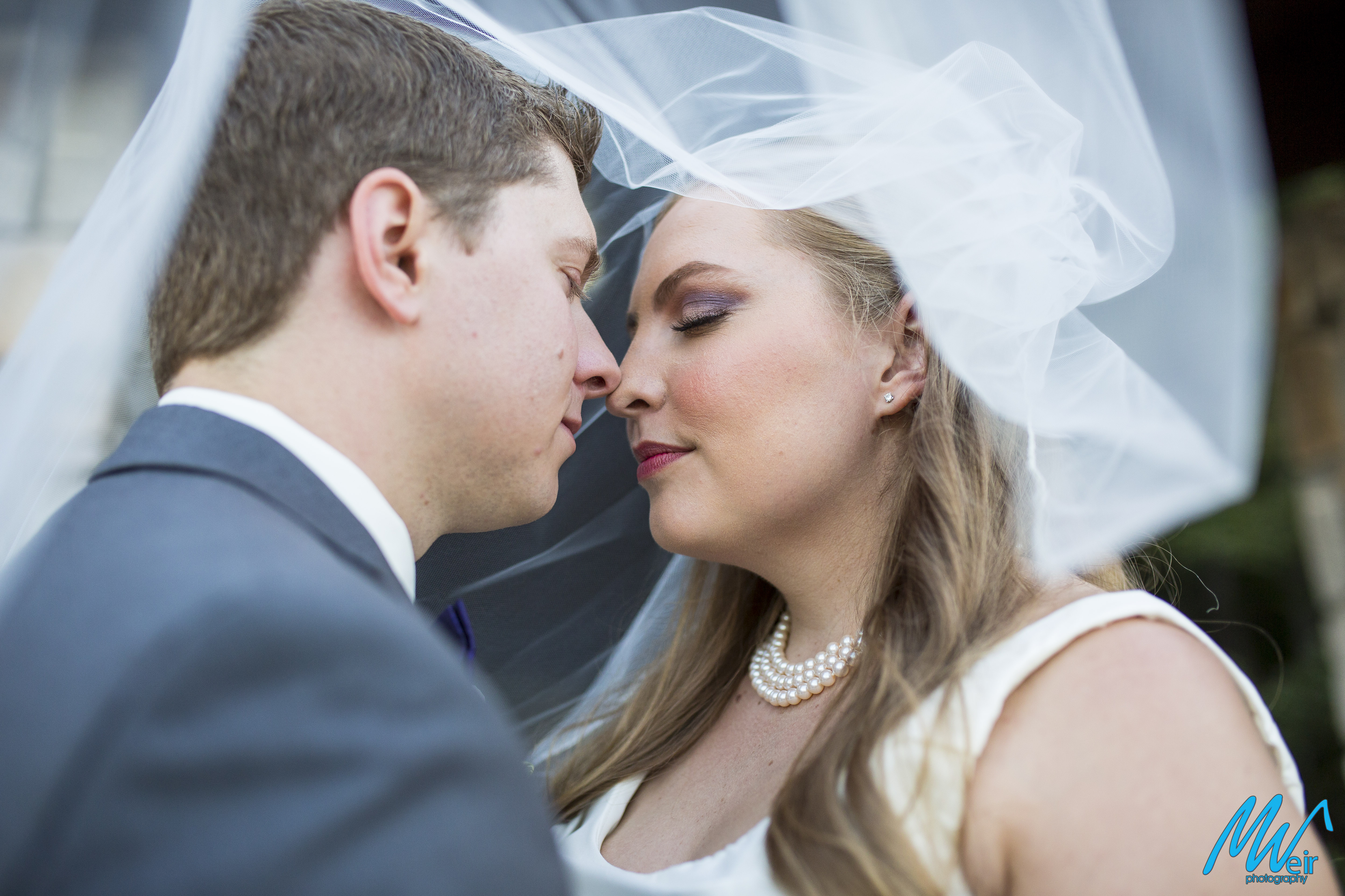 bride and groom nose to nose under veil