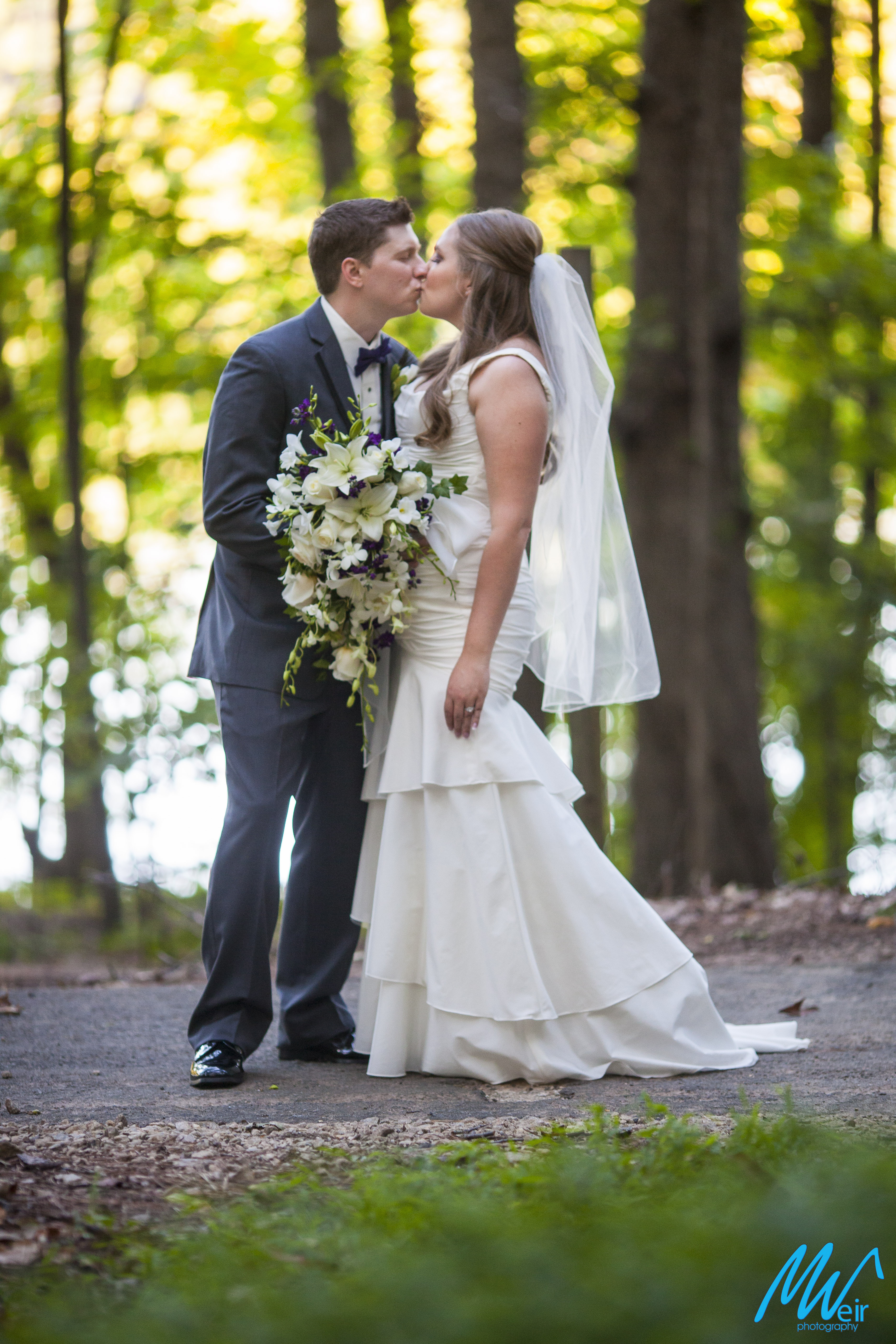 bride and groom kiss in the woods