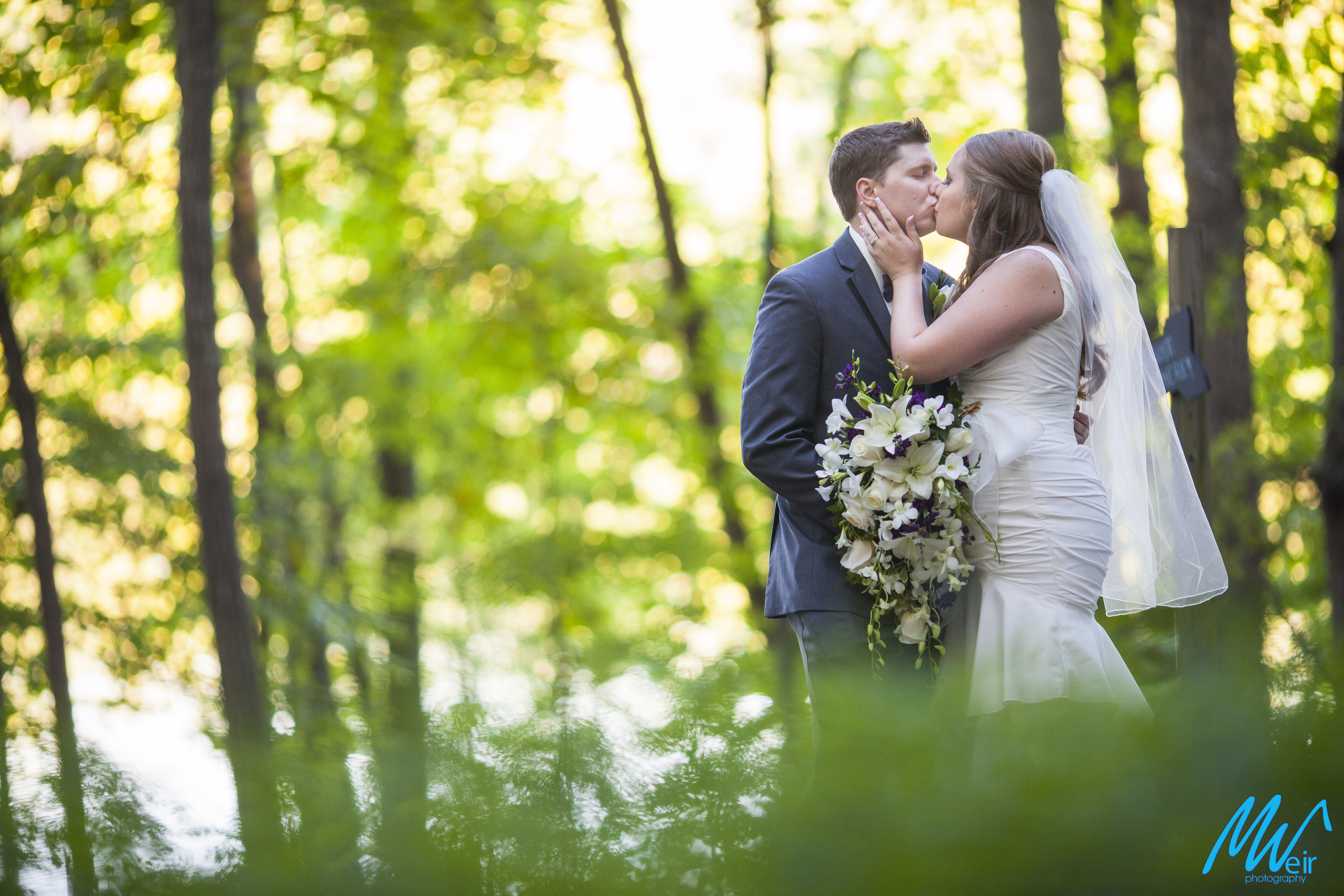 bride and groom kiss in the woods
