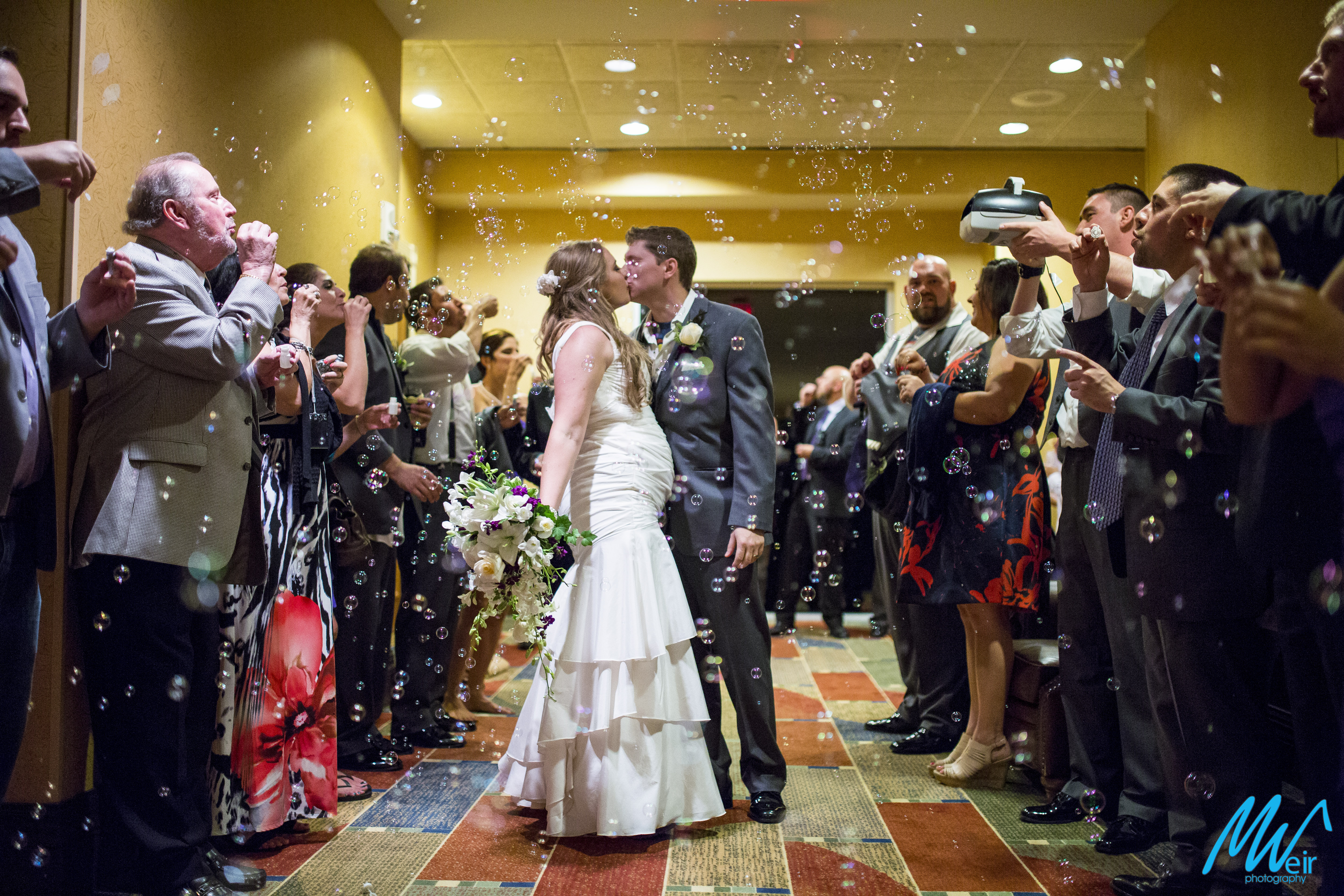 bride and groom exit inside the hotel with tons of bubble