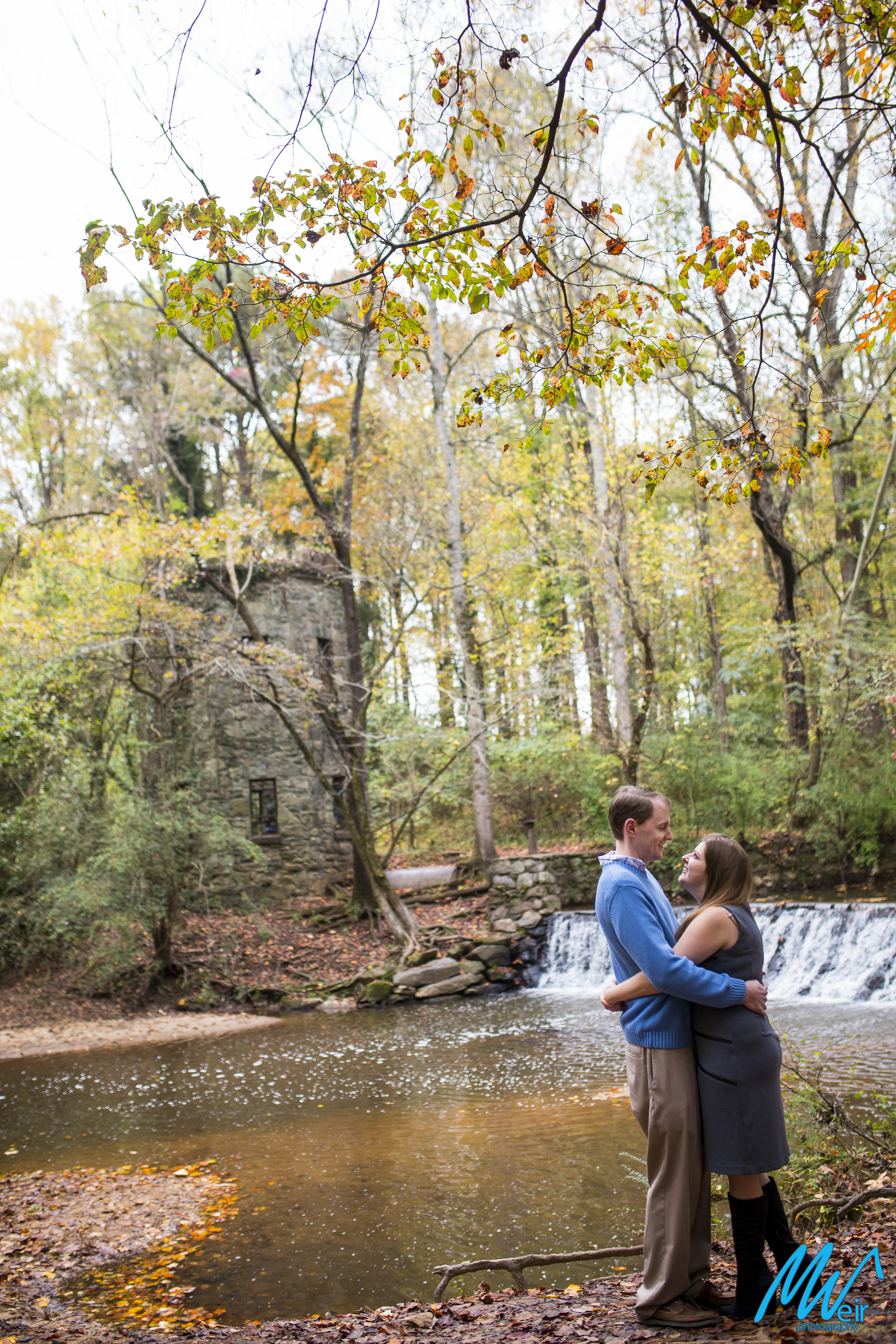 couple hug each other in front of a waterfall