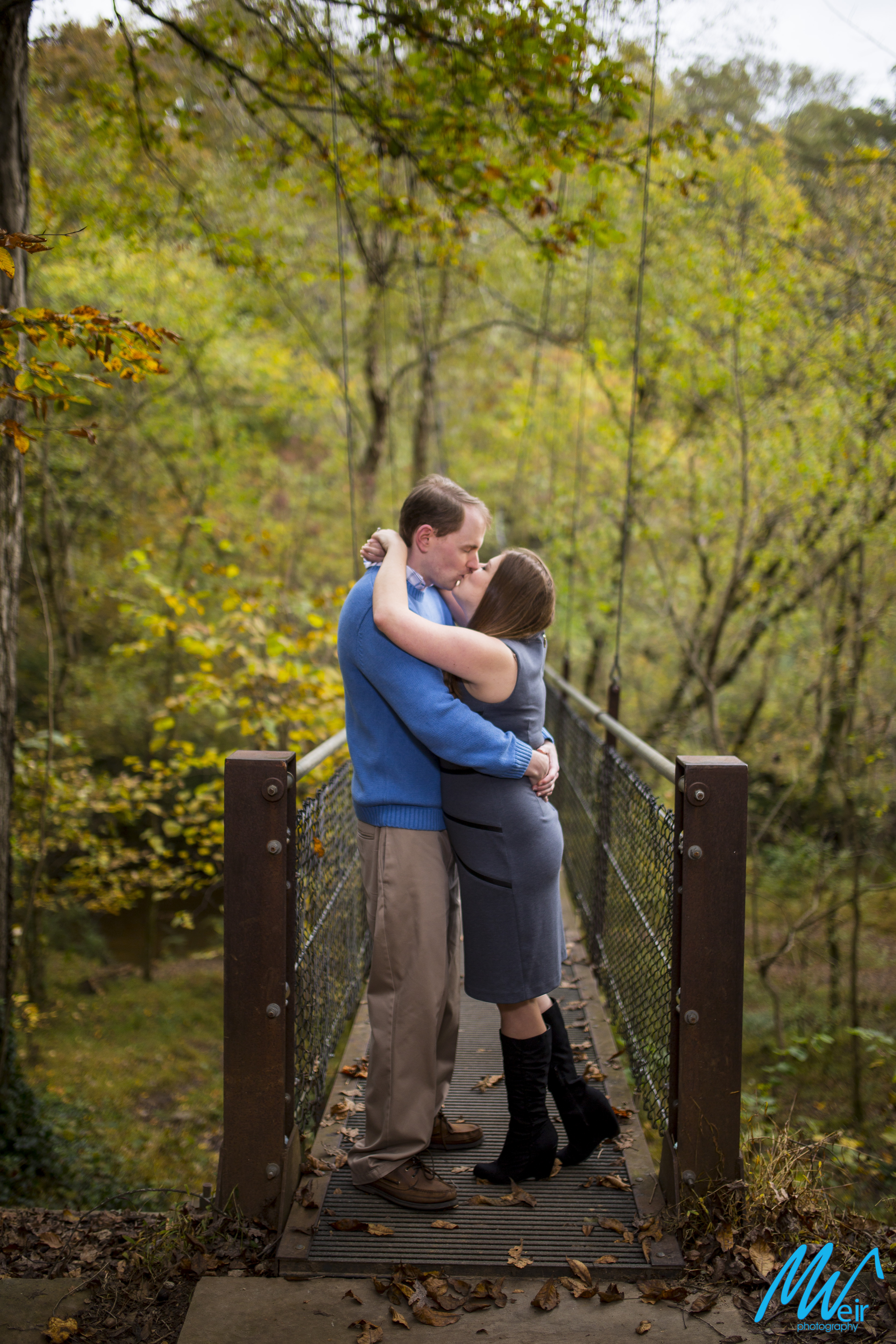 couple kiss at the end of a suspension bridge