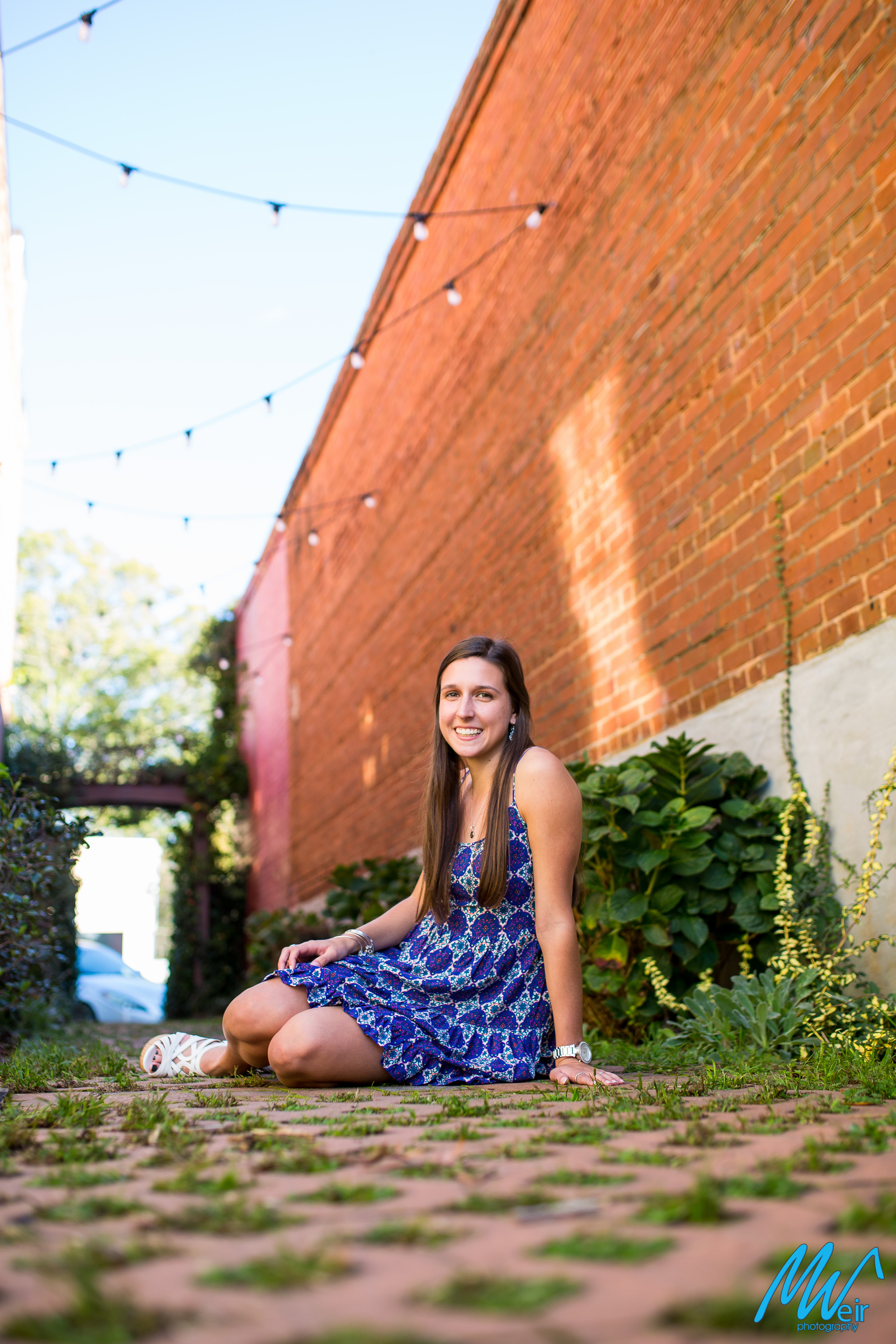 high school senior sitting in a brick paver alleyway