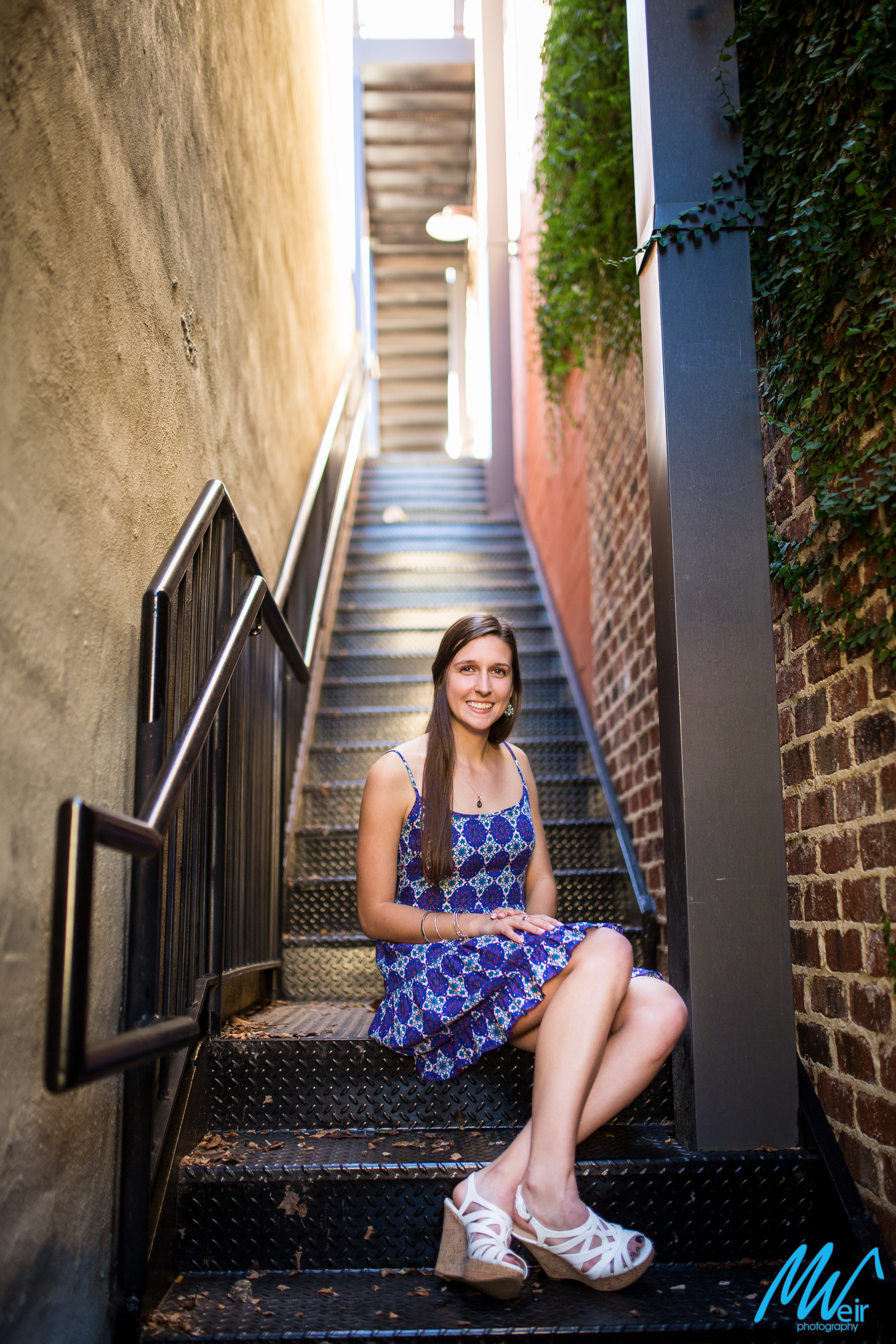 high school senior sitting on black stairs in an alley