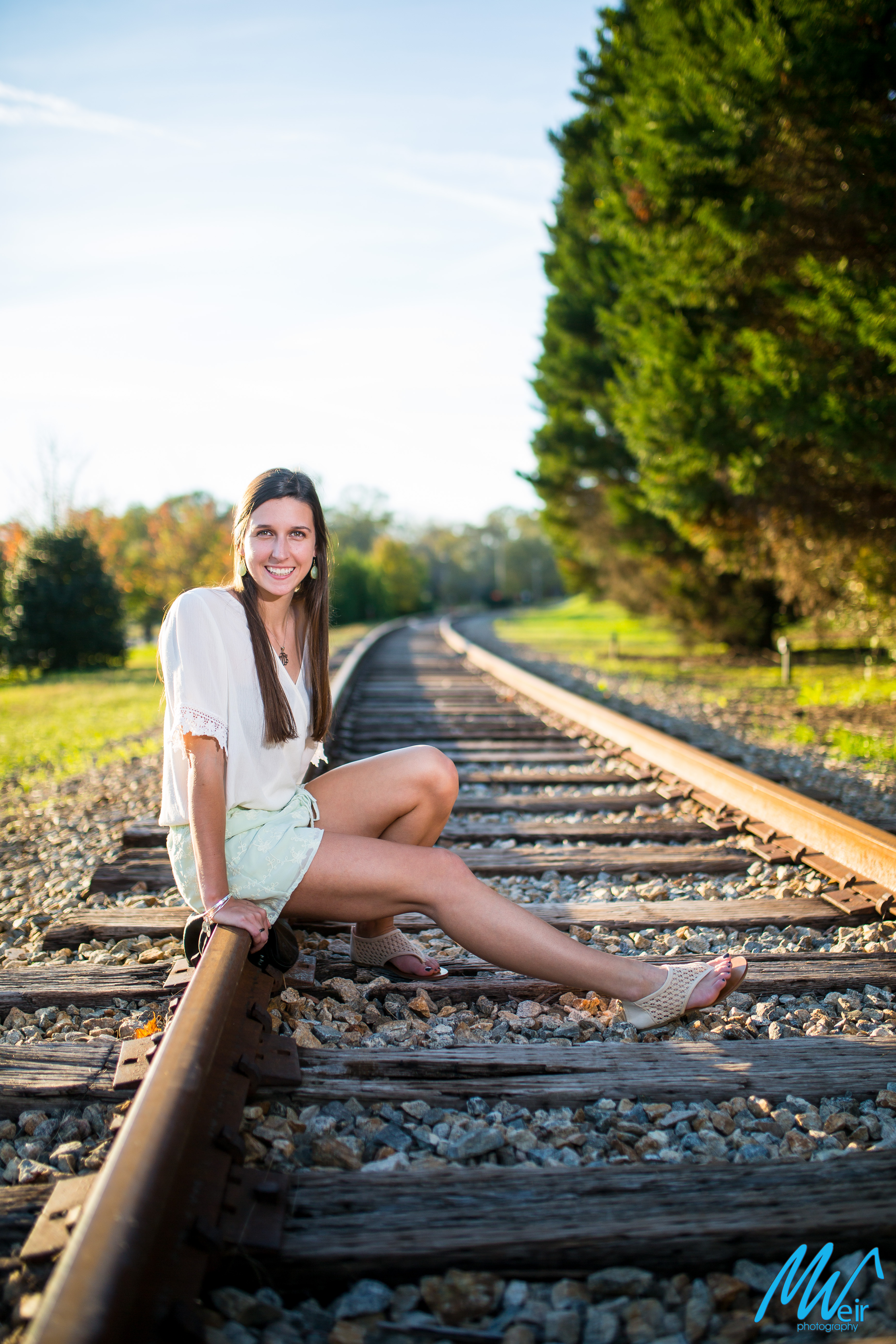 high school senior girl sitting on railroad tracks