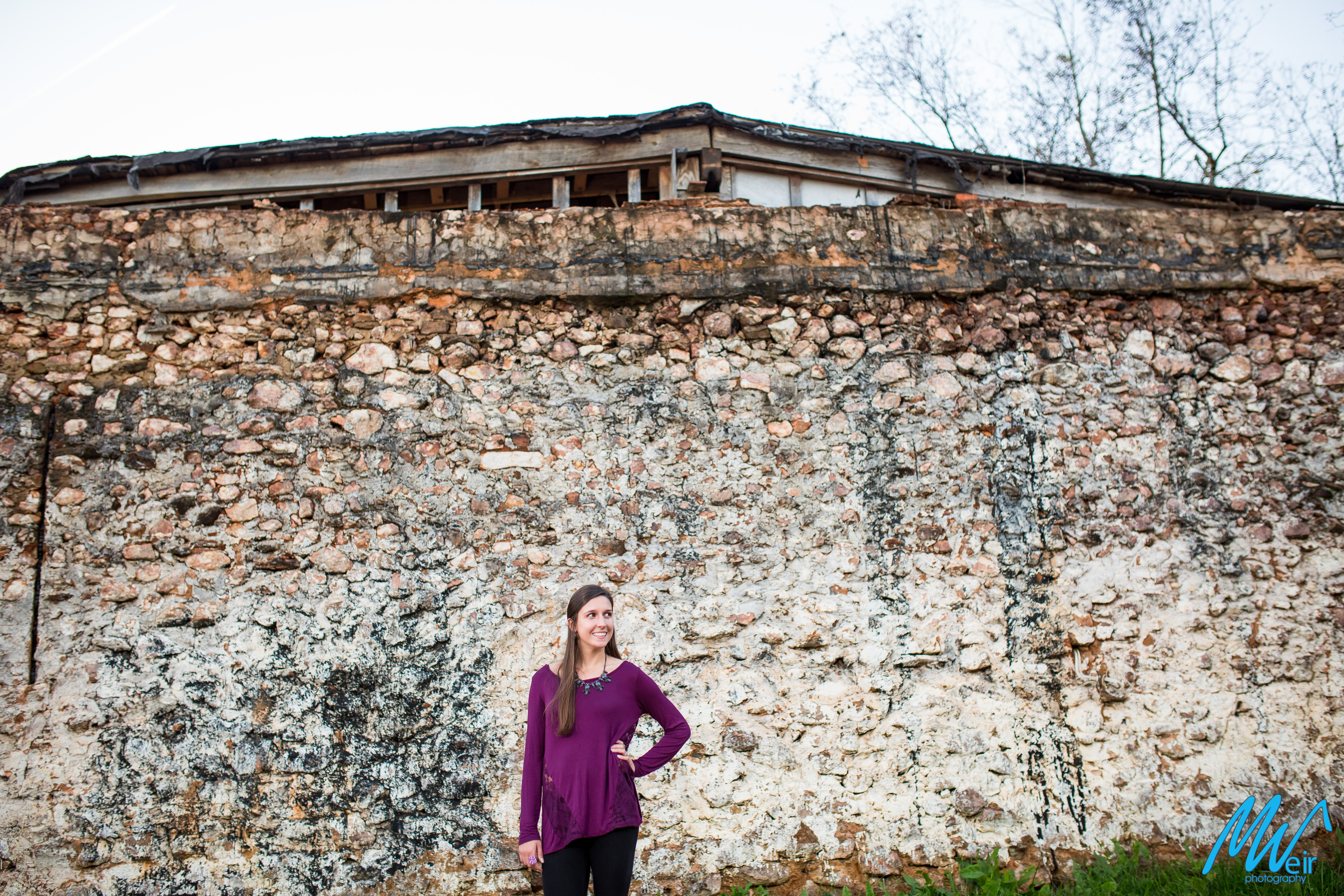 high school senior girl standing in front of old stone wall