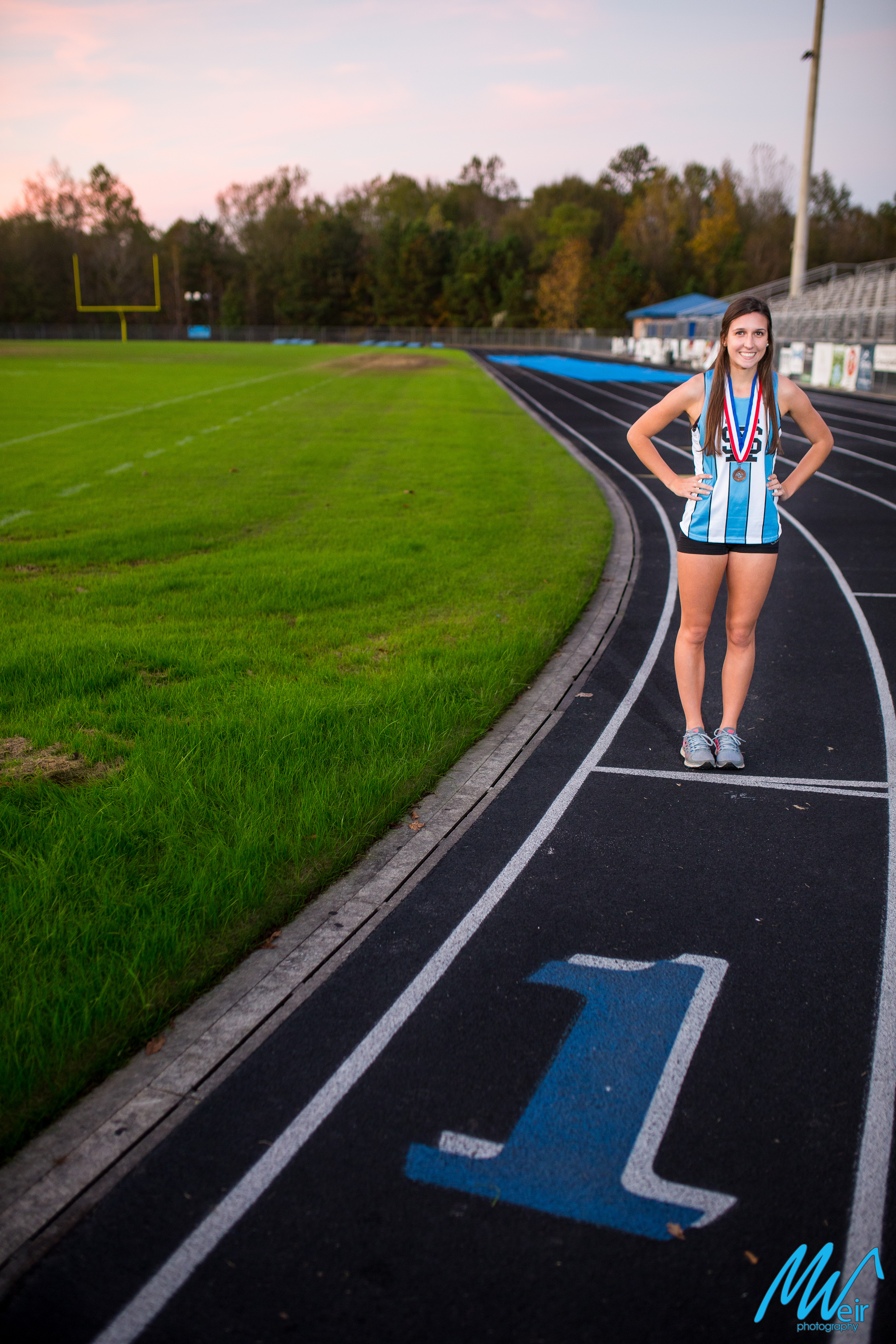 high school senior girl in track outfit on school track