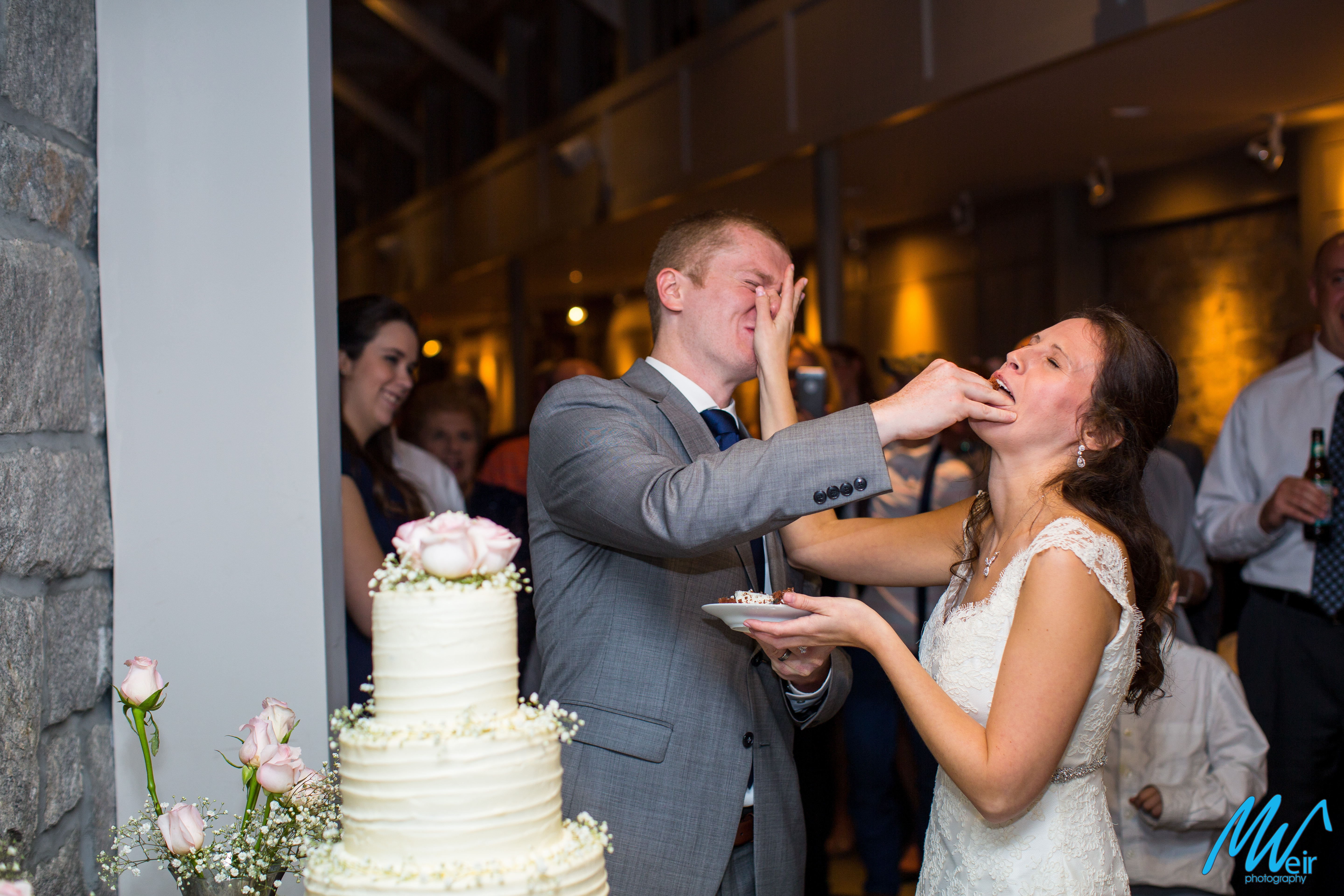 bride and groom smash cake in each others face