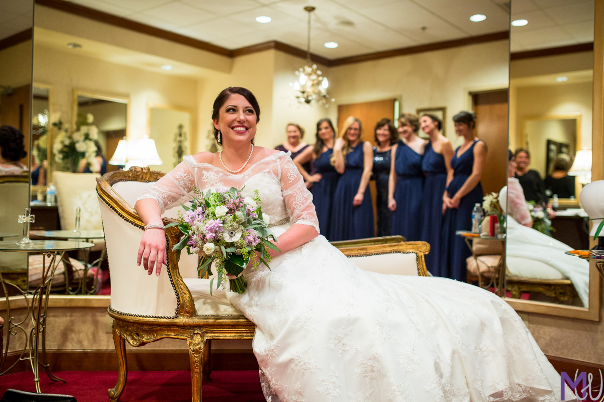 bride sitting on a chaise lounger with bridesmaids
