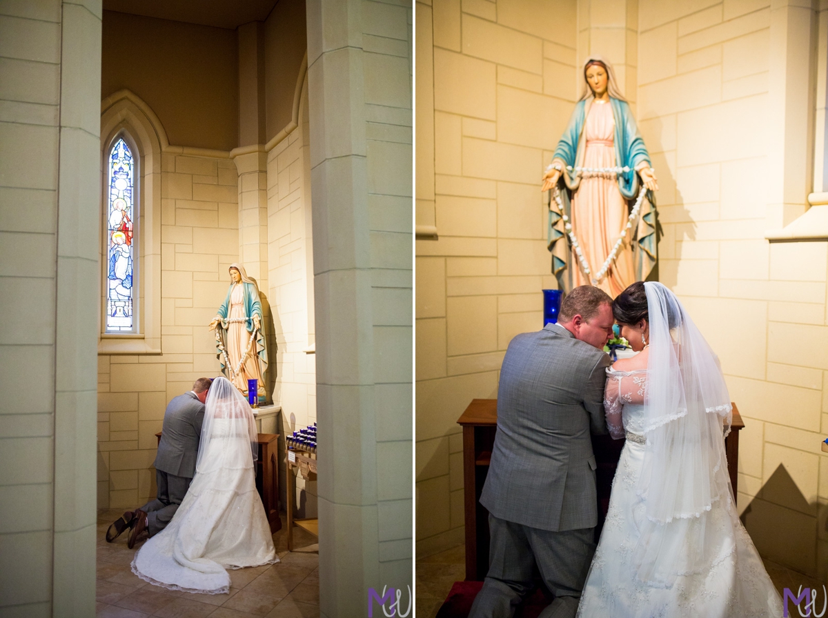 bride and groom praying at the statue of Mary