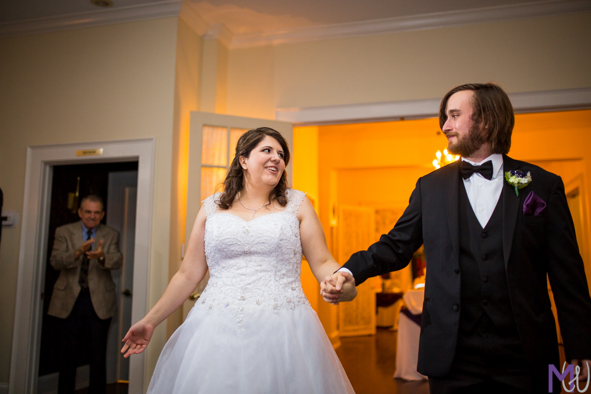 bride and groom walk in to wedding reception