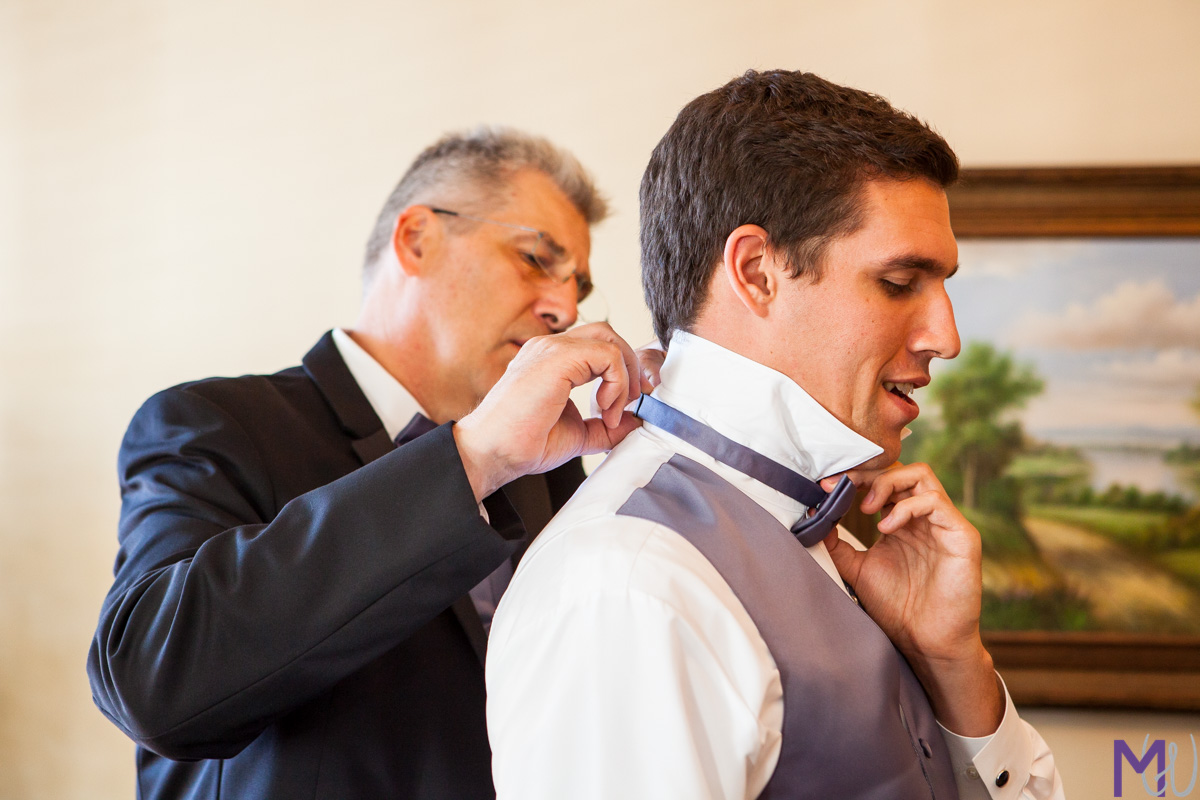 father helps groom with his tie