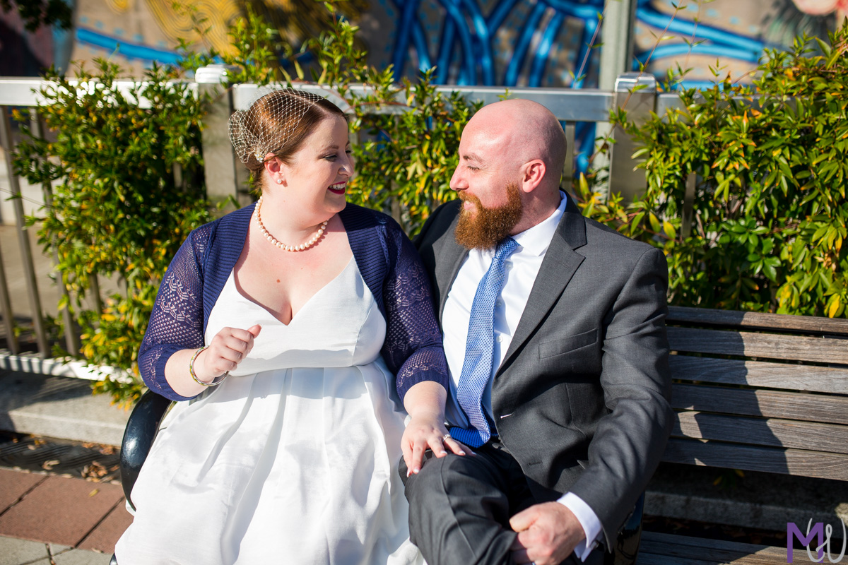 bride and groom kissing on a bench