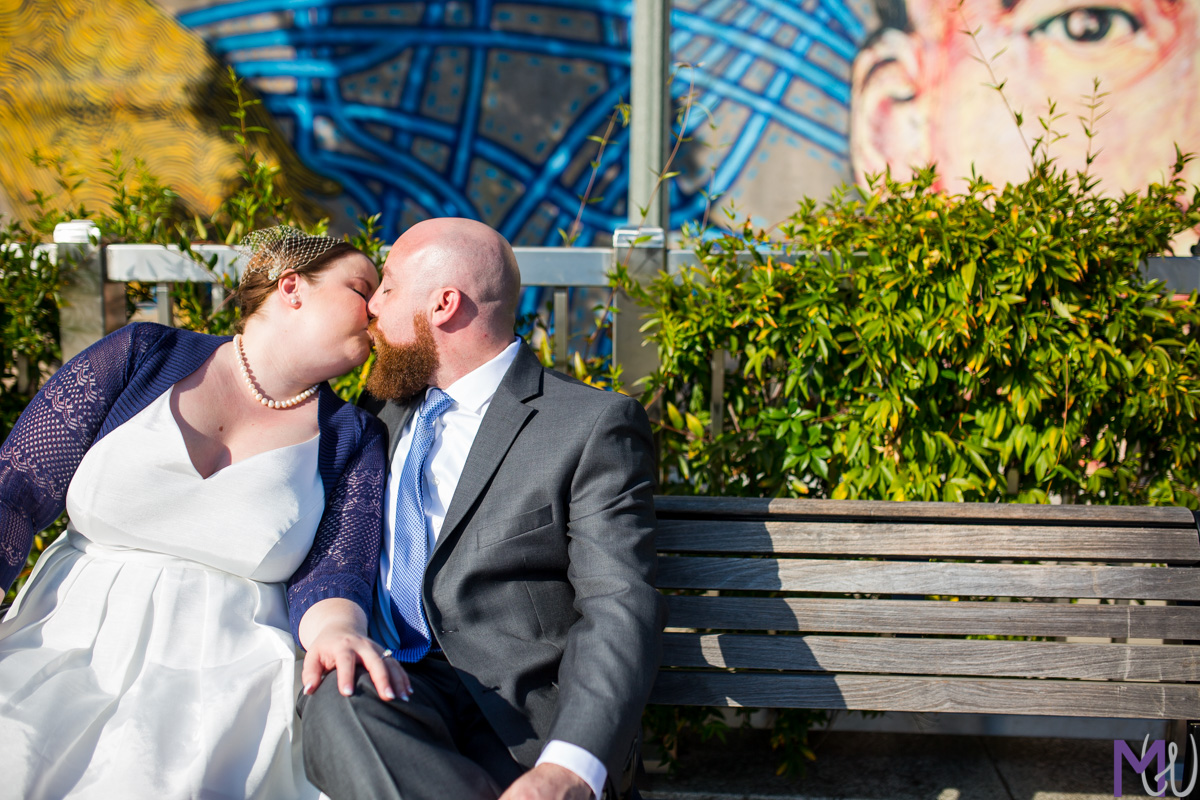 bride and groom kissing on a bench