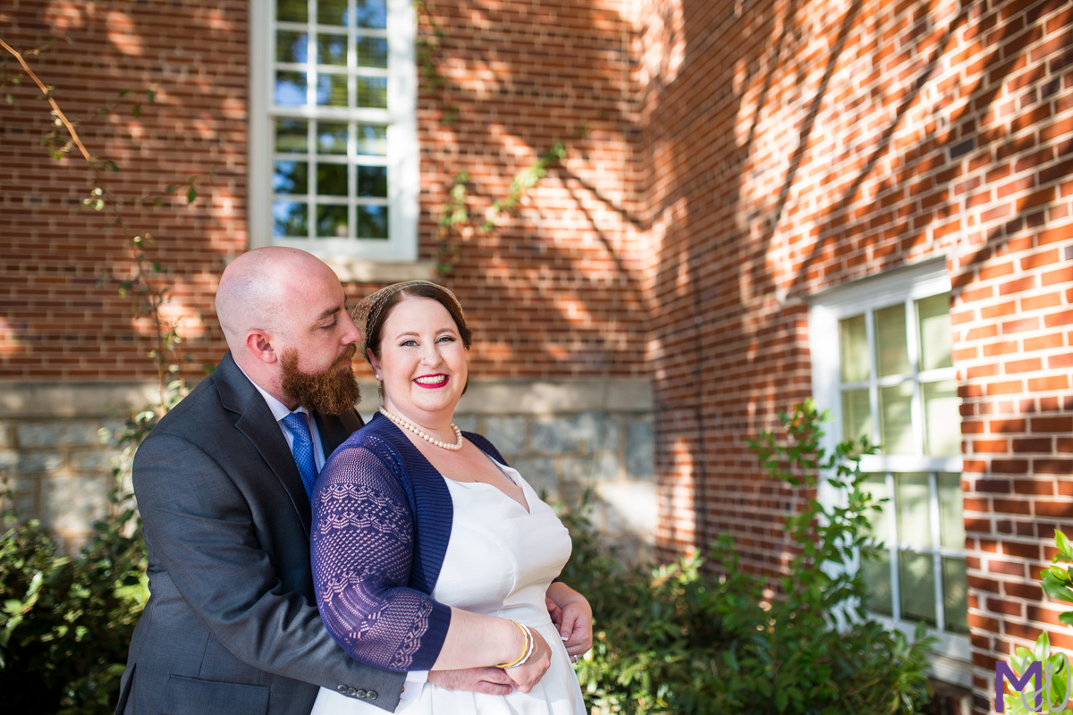 bride and groom in front of brick building