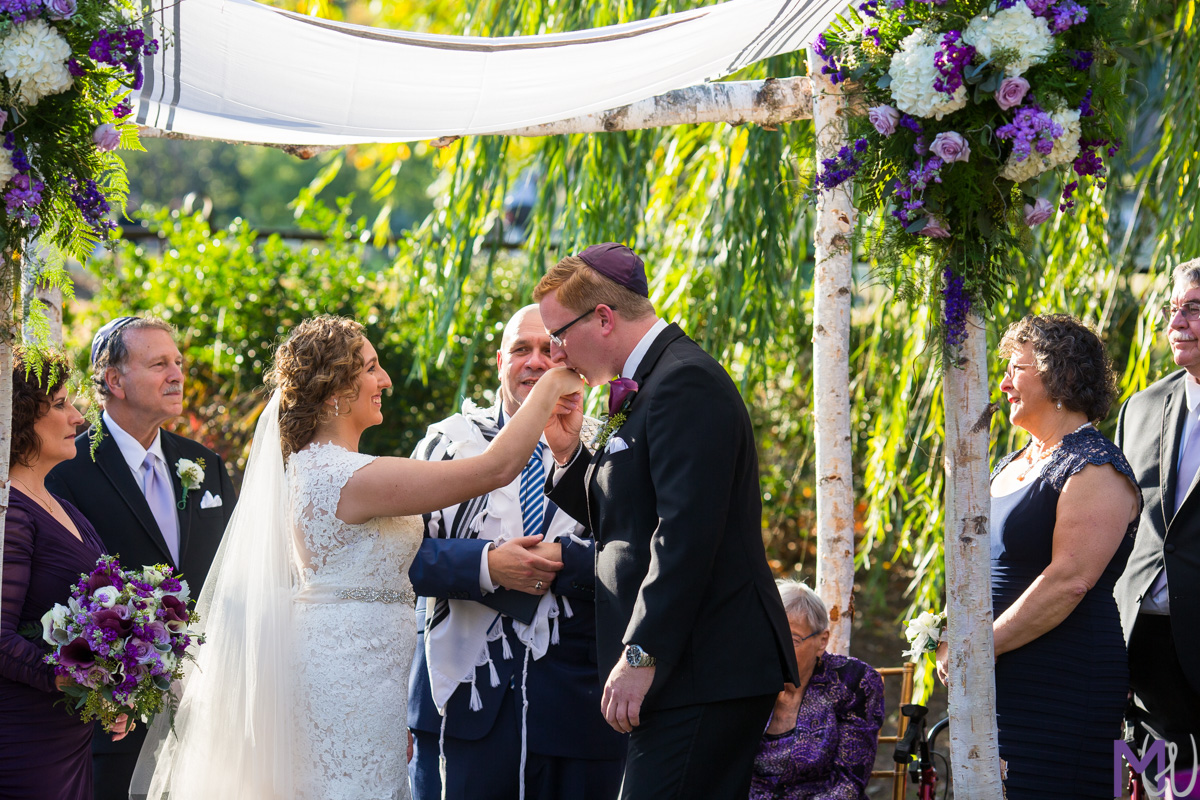 groom kisses brides hand during jewish wedding ceremony