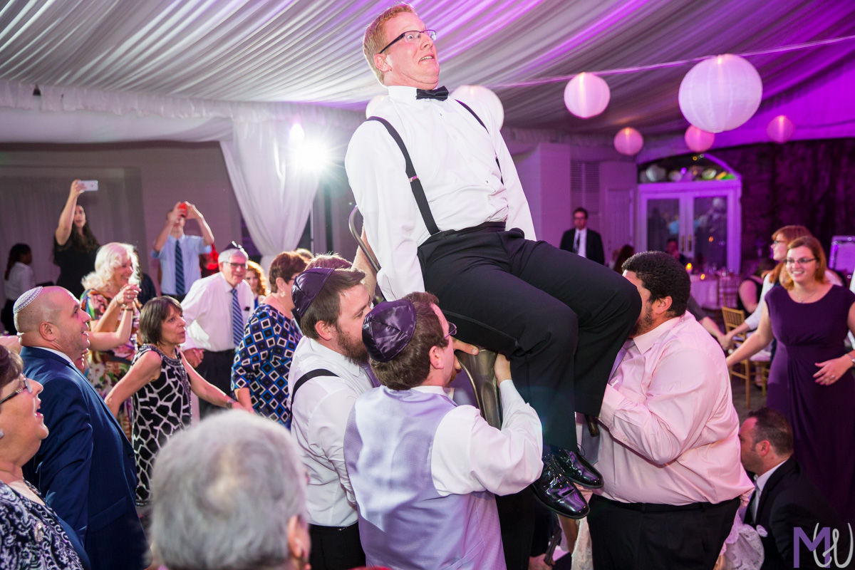 bride and groom lifted up on chairs during Hora