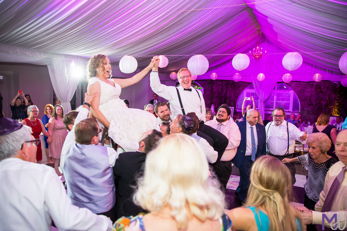 bride and groom lifted up on chairs during Hora
