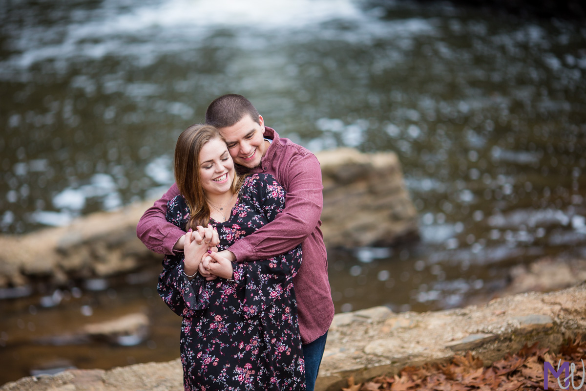 couple standing in front of a waterfall at freeman mill park