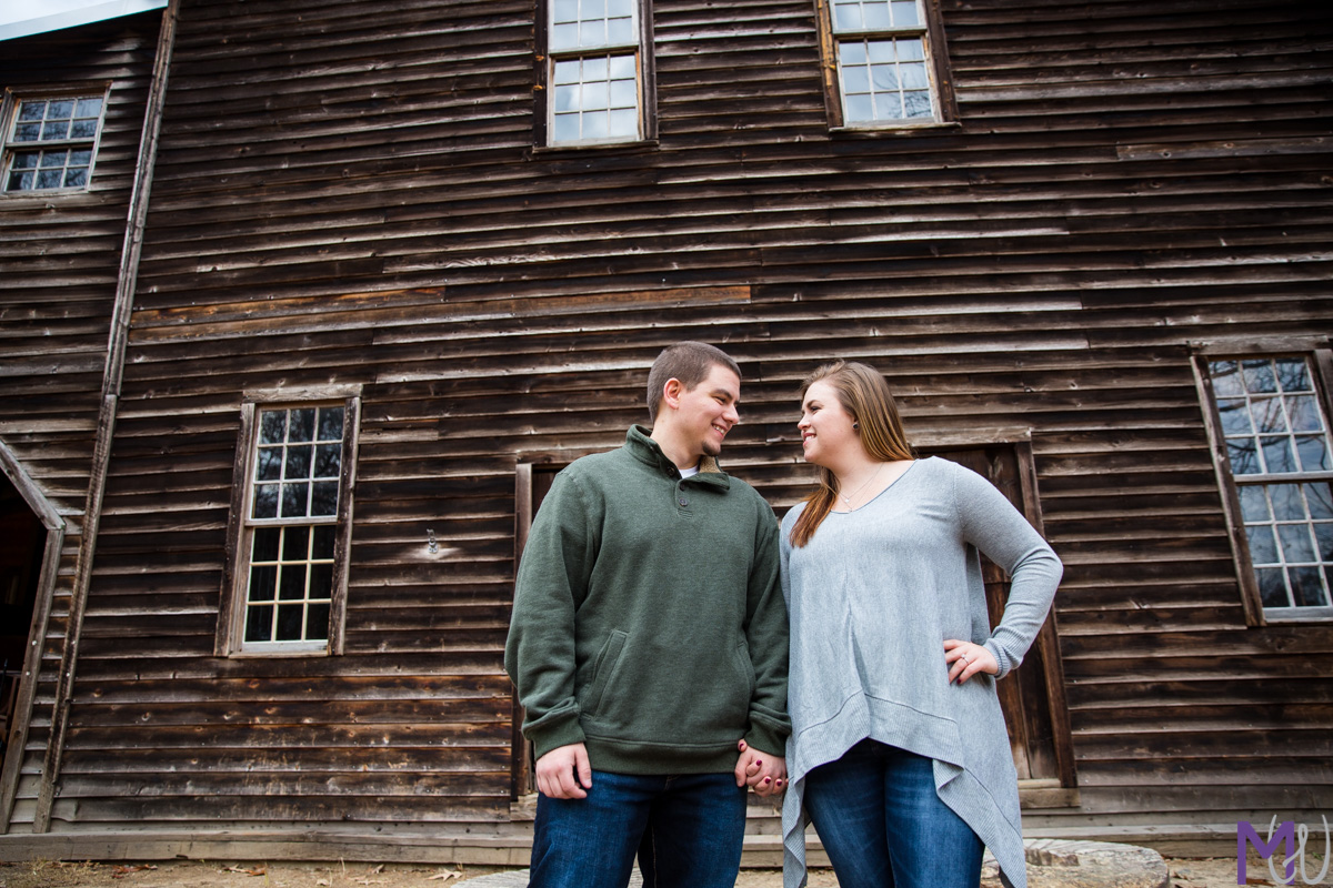 couple standing in front of a old wood mill building