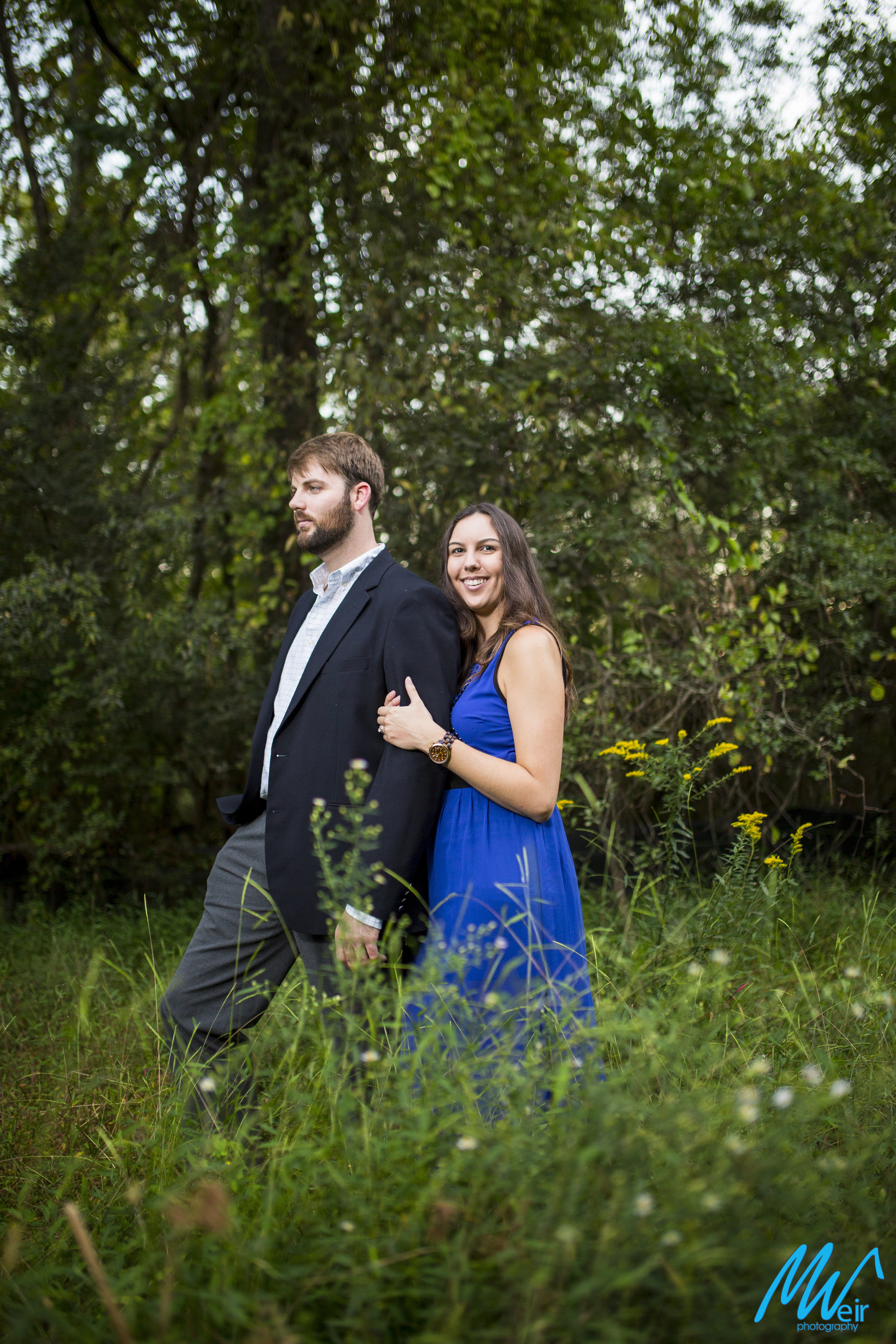 engaged couple standing in a tall grass field