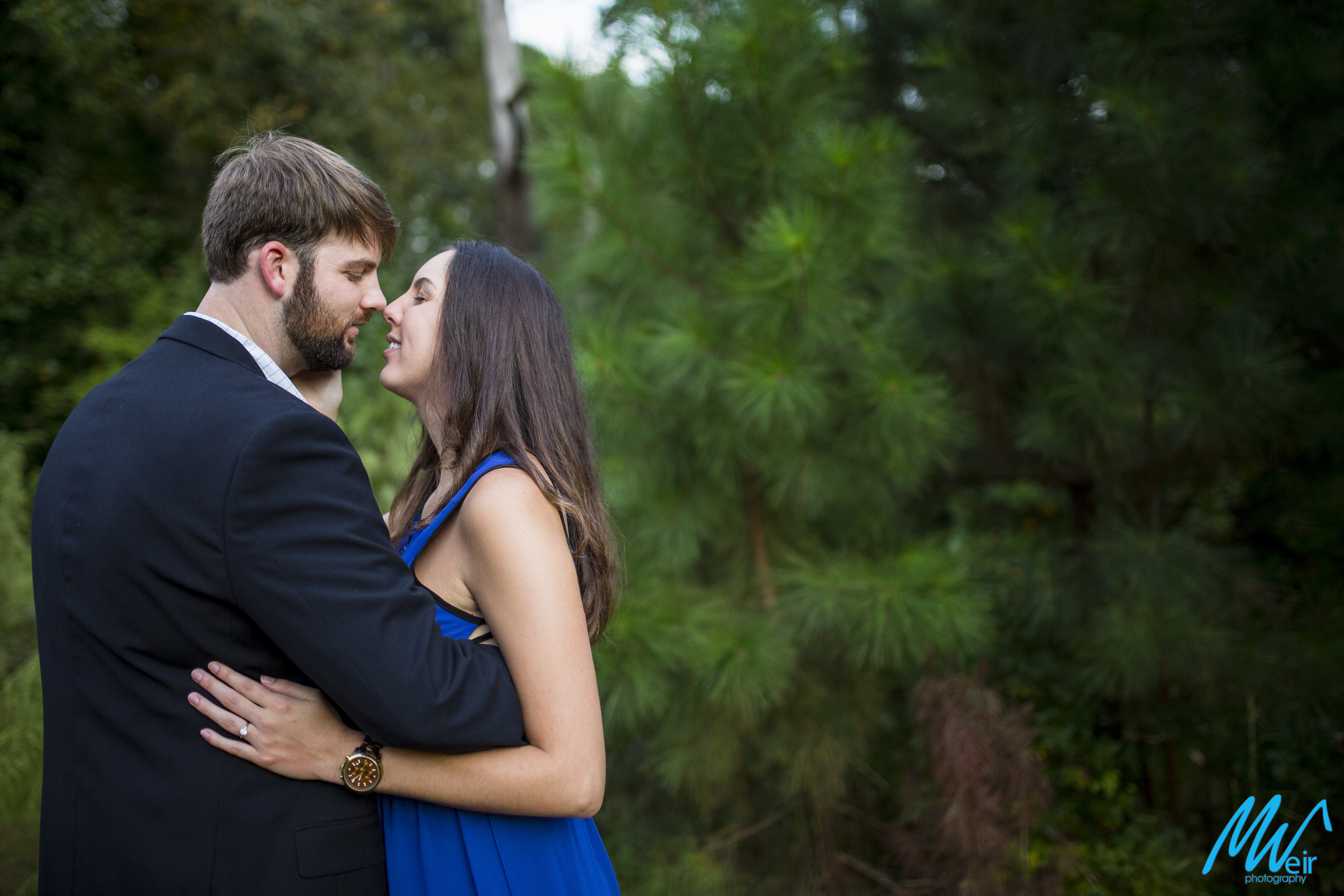 bride and groom almost kiss in front of pine trees