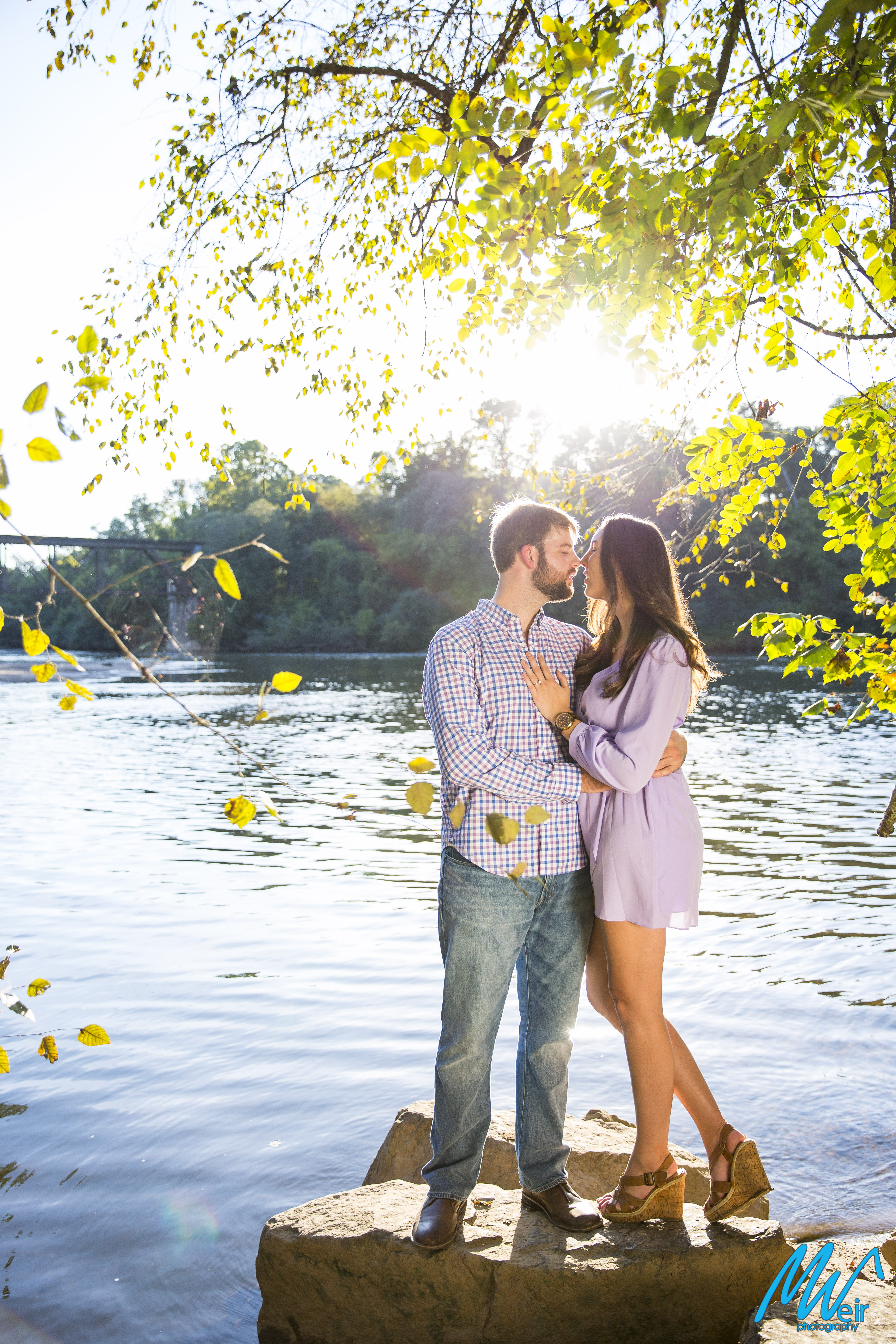 bride and groom stand on rocks by the Chattahoochee river