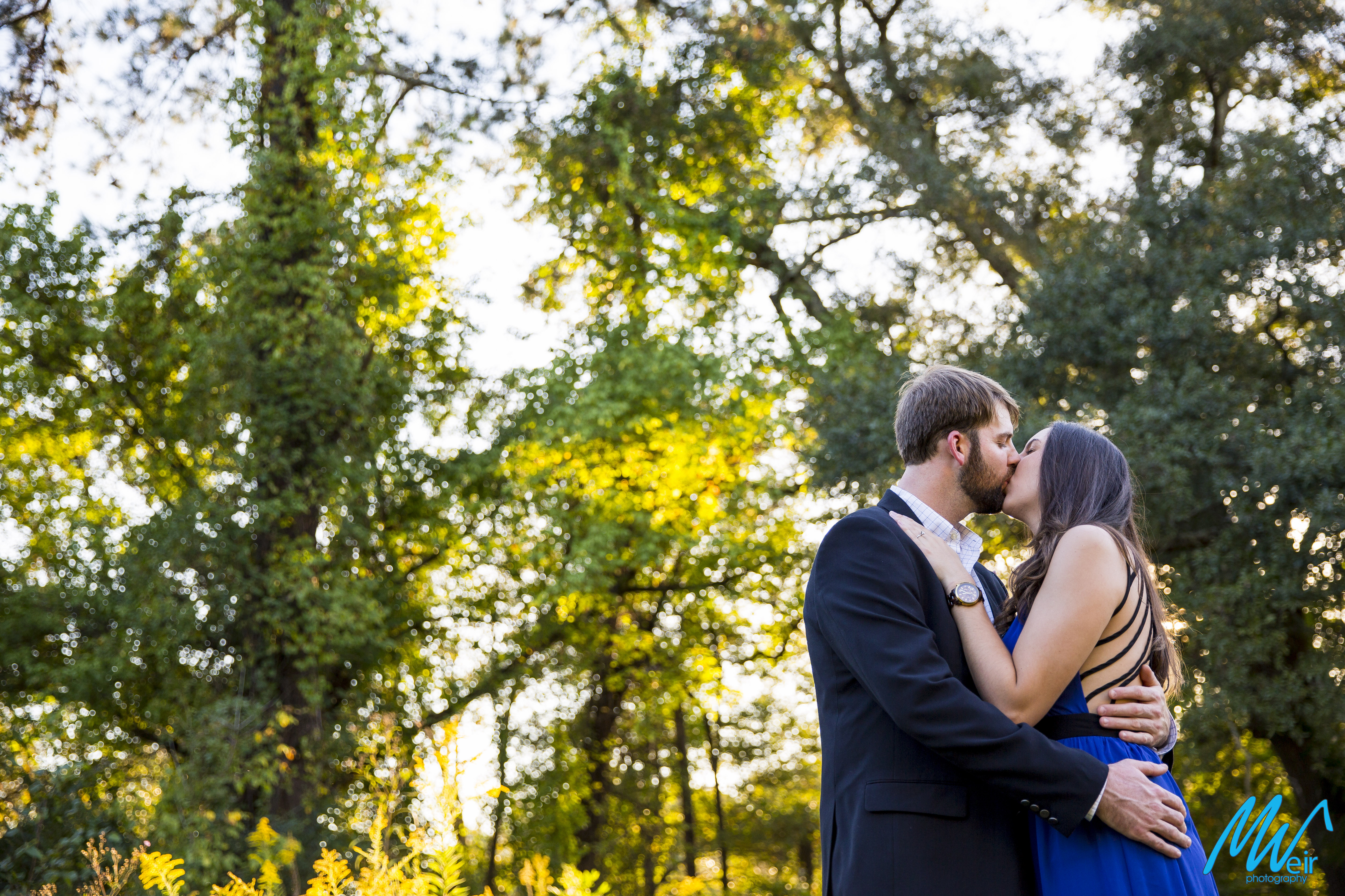 bride and groom kiss in a sun kissed forest