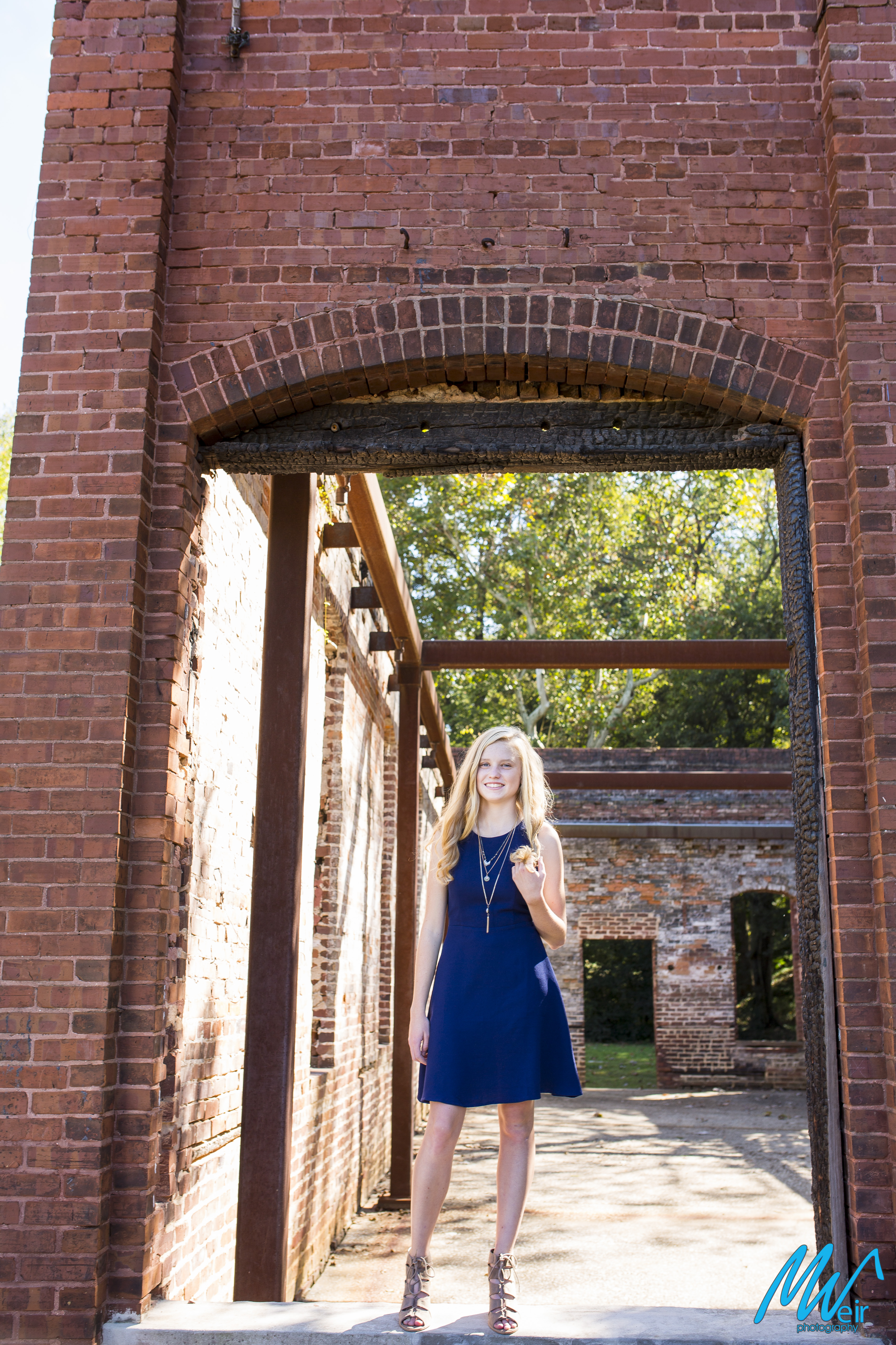 high school senior in navy dress in front of brick building