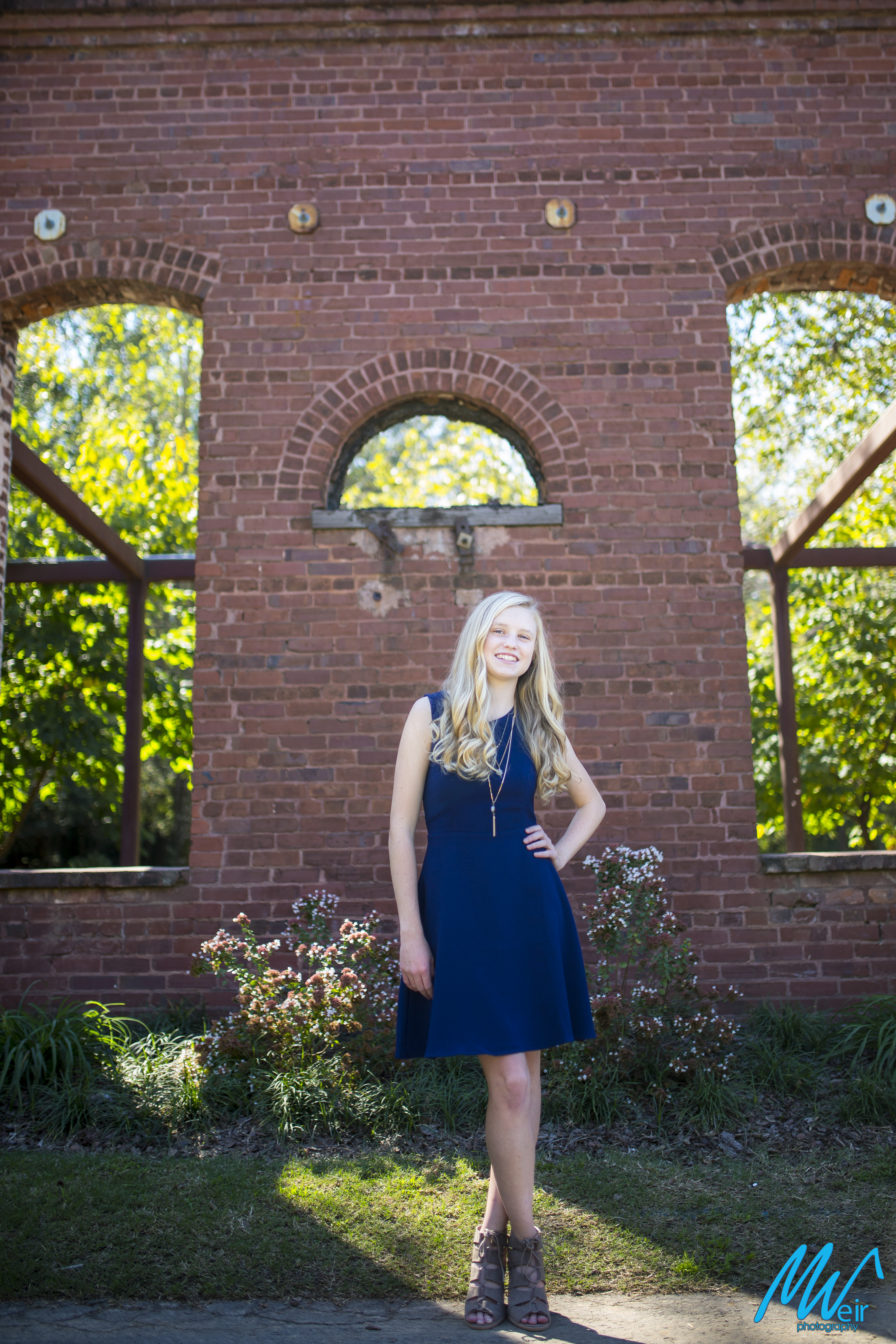 high school senior in navy dress in front of brick building